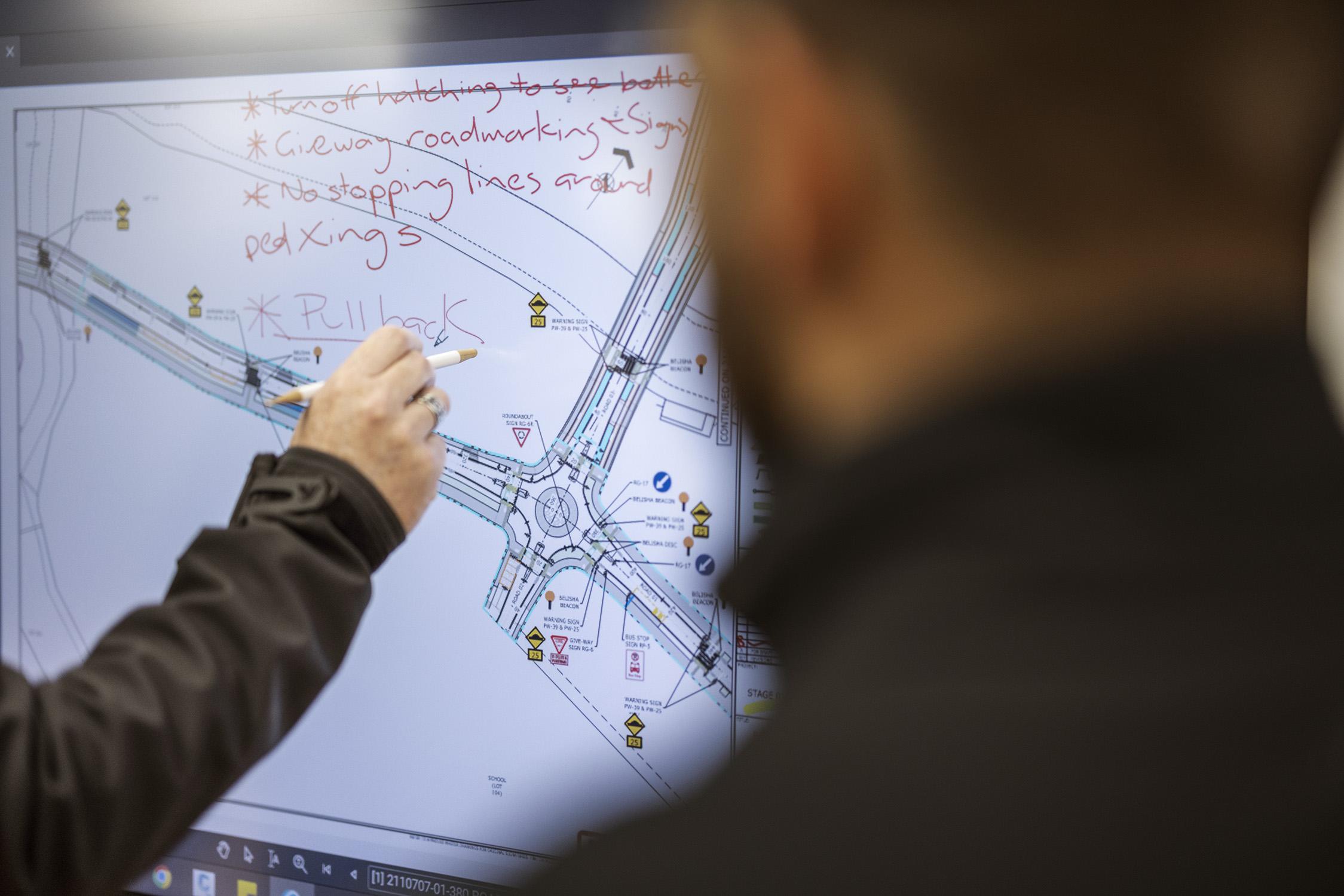 Two Harrison Grierson employees working road plans using a digital whiteboard.