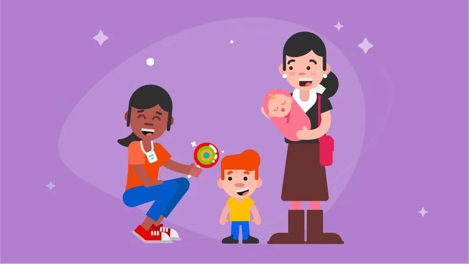 A smiling volunteers bending down to offer a lollipop to a boy and his mom holding a baby.