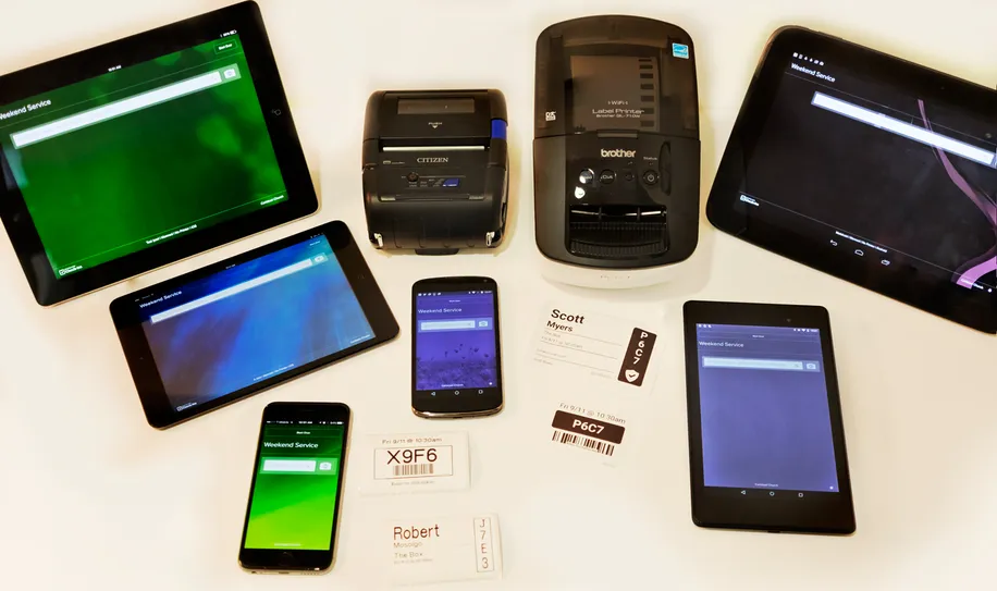 Two label printers on a table with two phones and four tablets of different sizes. 