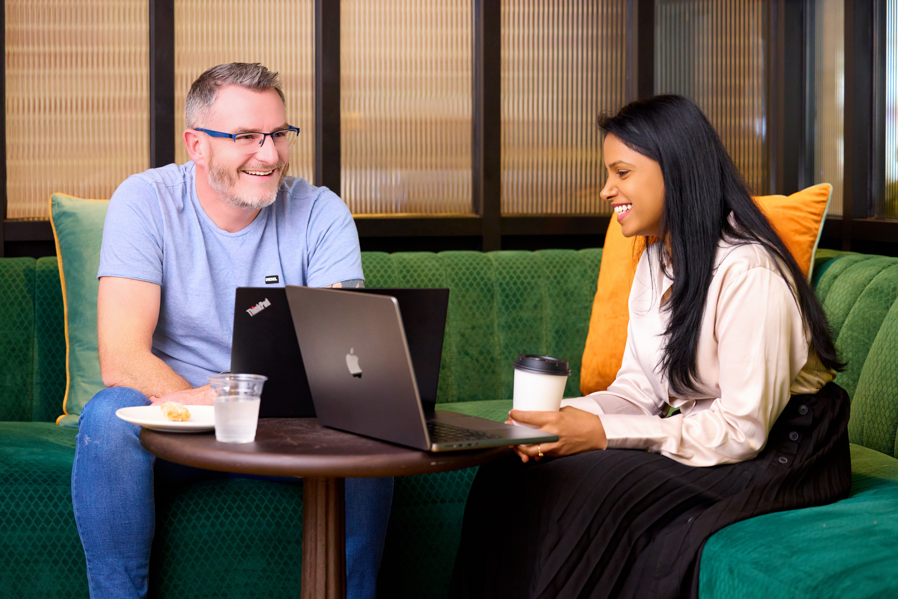 A man and a woman sit together with their laptops open