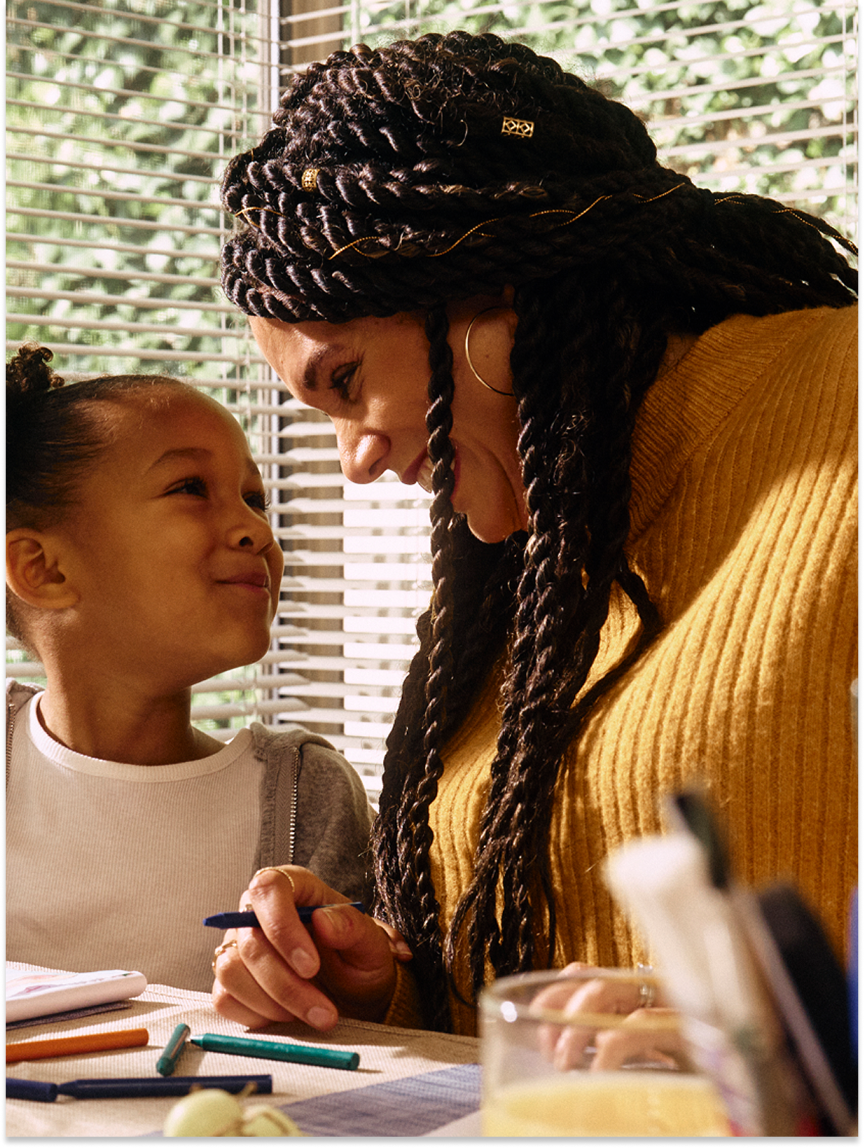 A nurse and her daughter at the table, coloring and smiling.