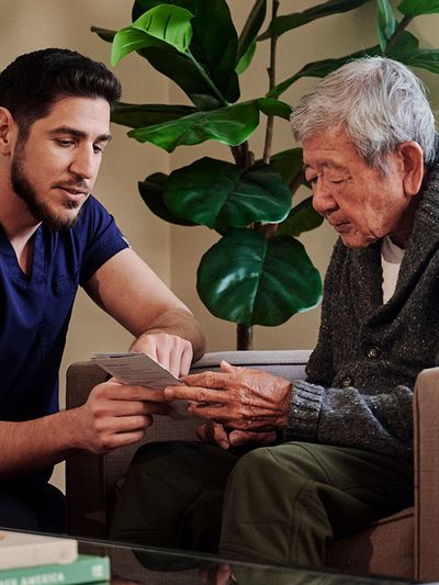Male nurse providing assistance to a seated patient.