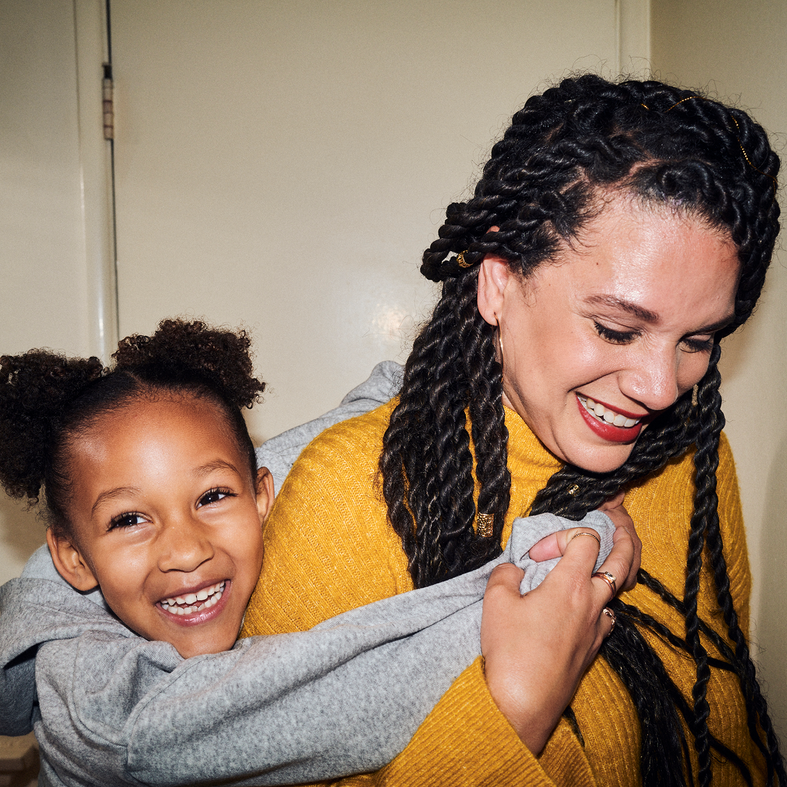An off-duty nurse enjoys time with her young daughter. The daughter has her hands around the mother's neck and they're both smiling.
