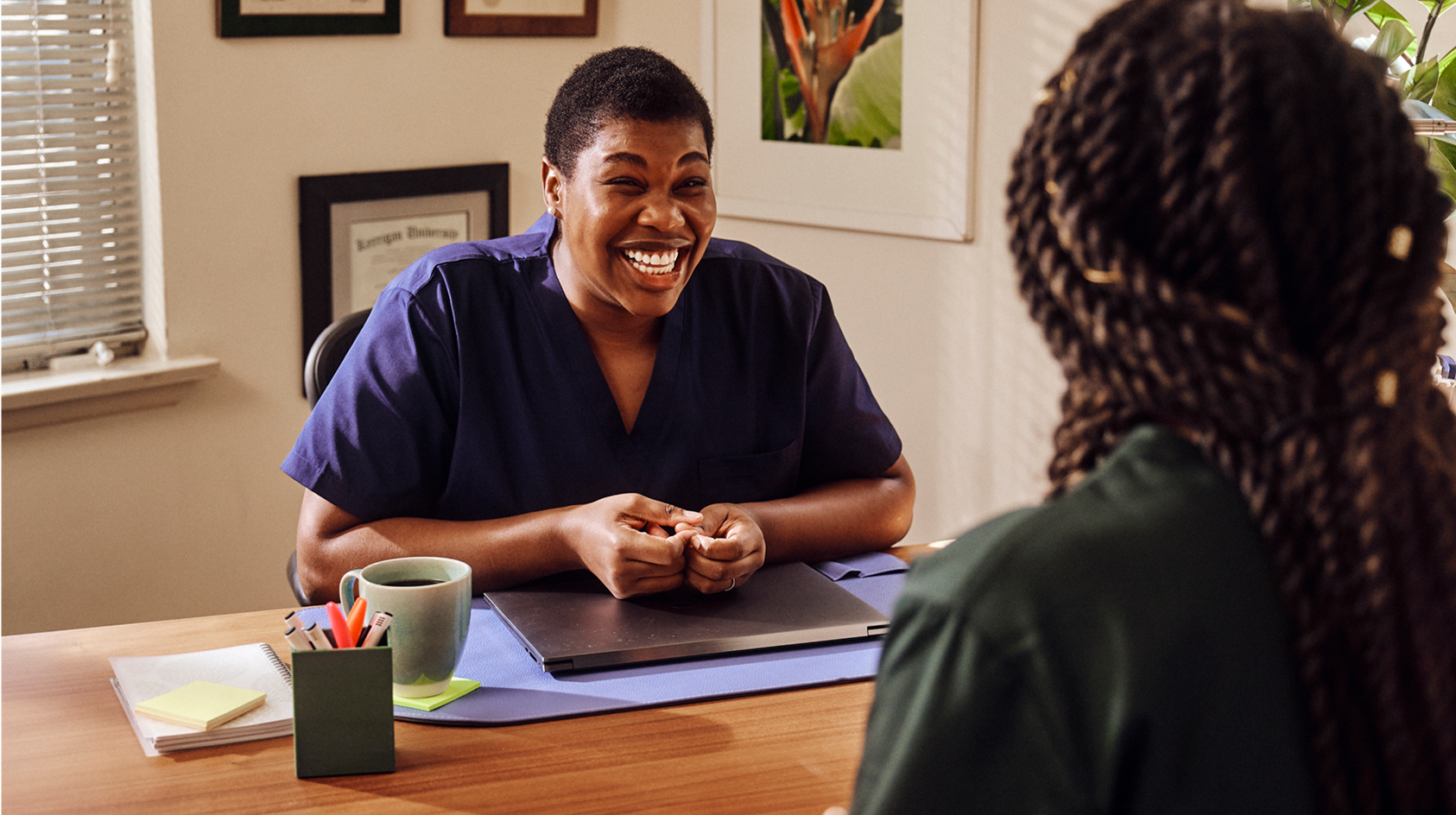 An independent professional wearing dark green scrubs talking to an administrator wearing navy scrubs