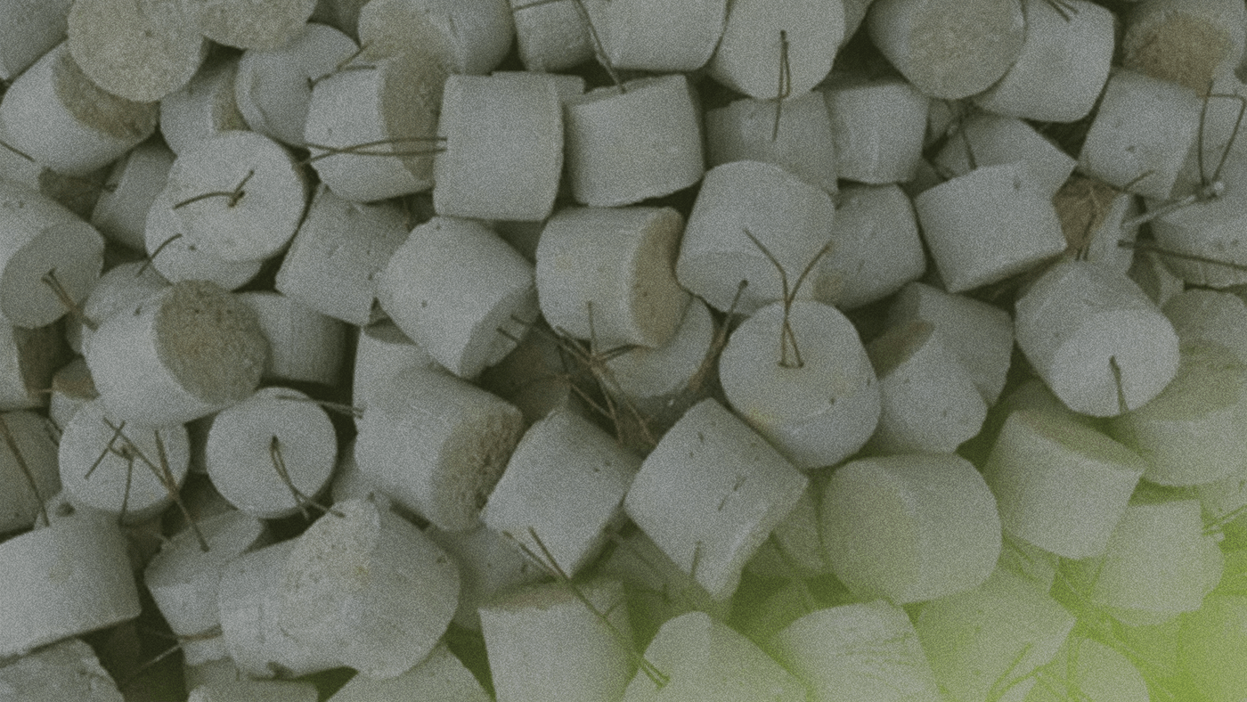 A pile of round, white briquettes with small metal handles, stacked closely together.
