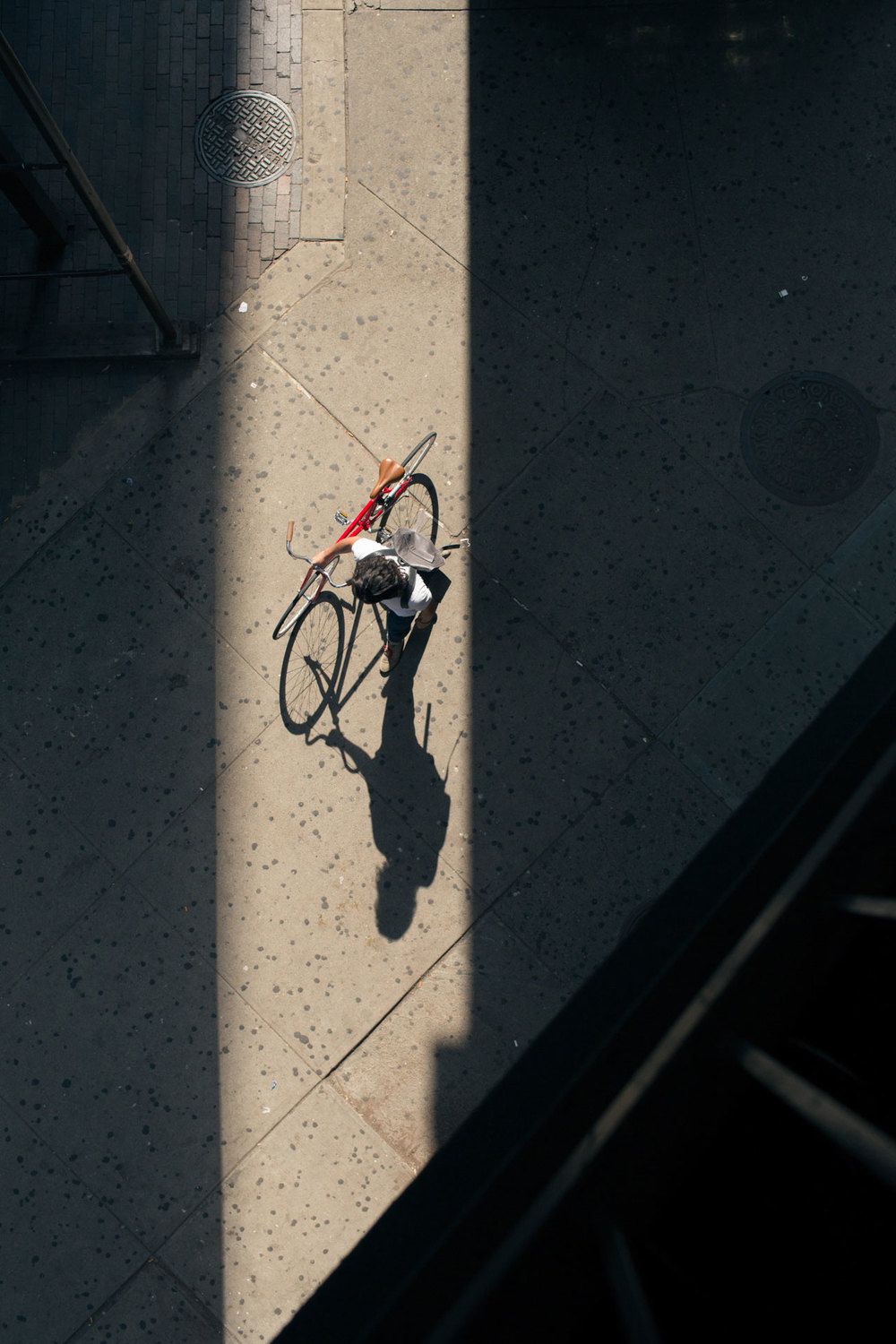 A cyclist walking with their bike in hand.