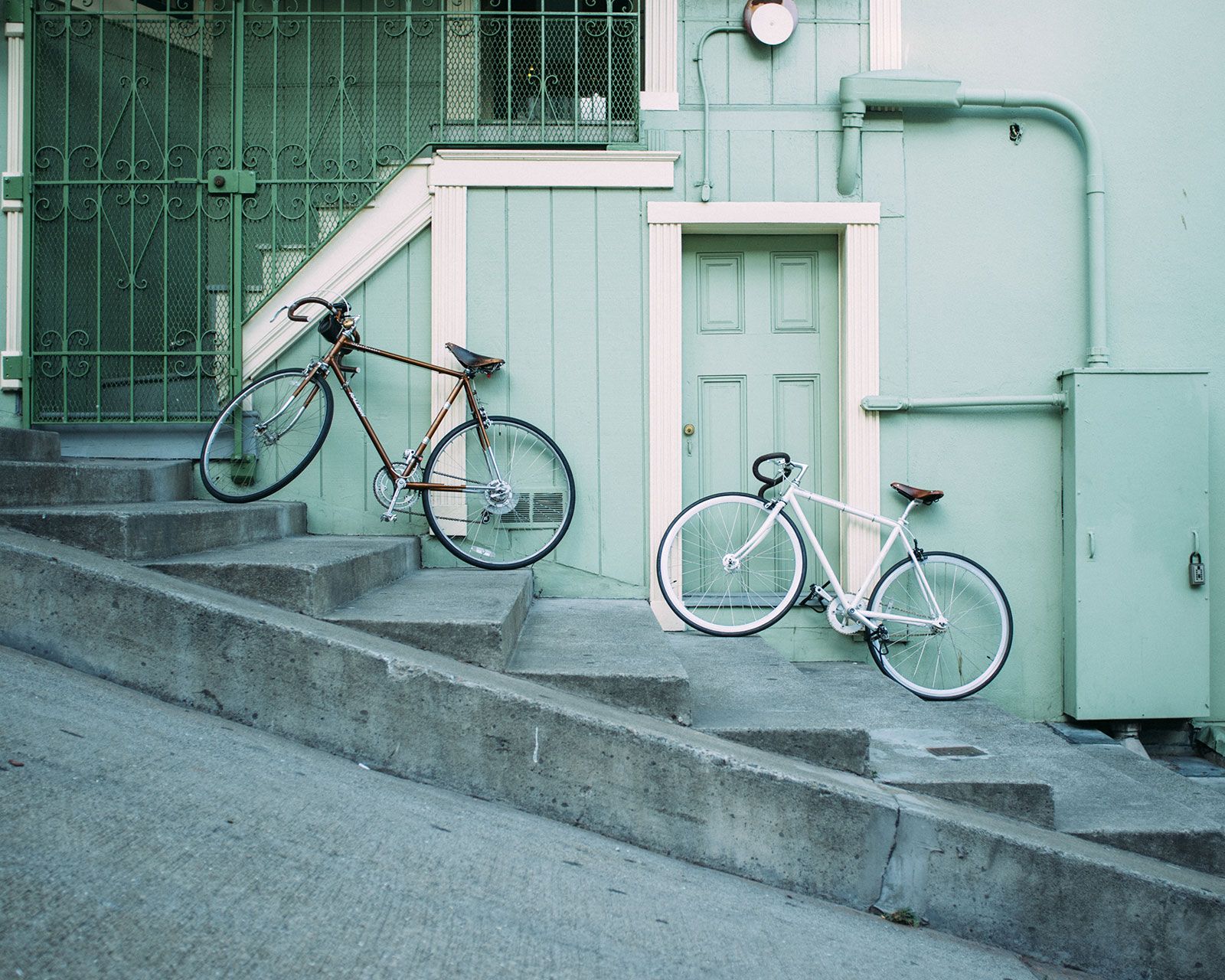 Two bicycles leaning against a building on a steep hill.
