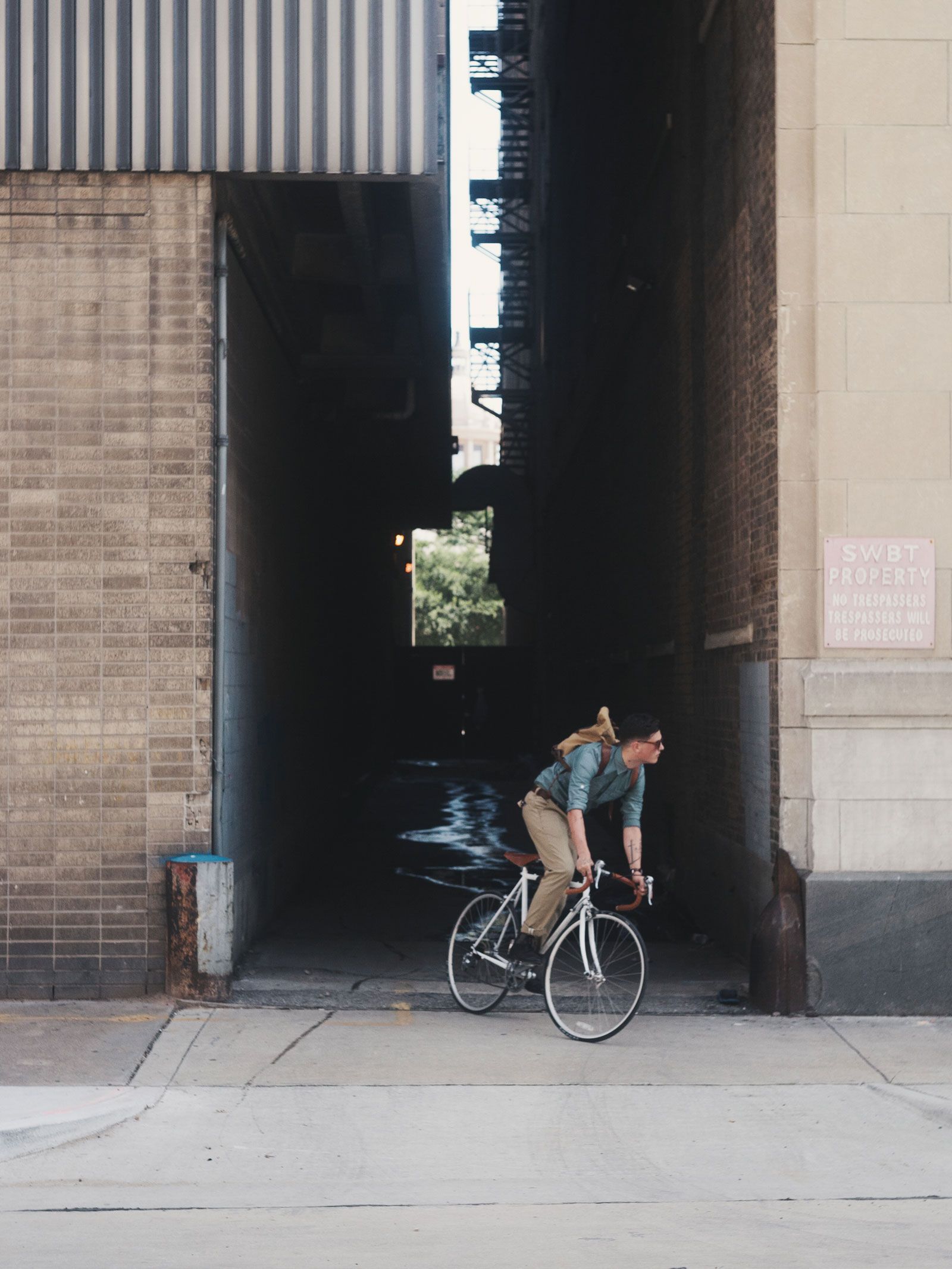 A cyclist jets out of an alleyway onto the sidewalk.