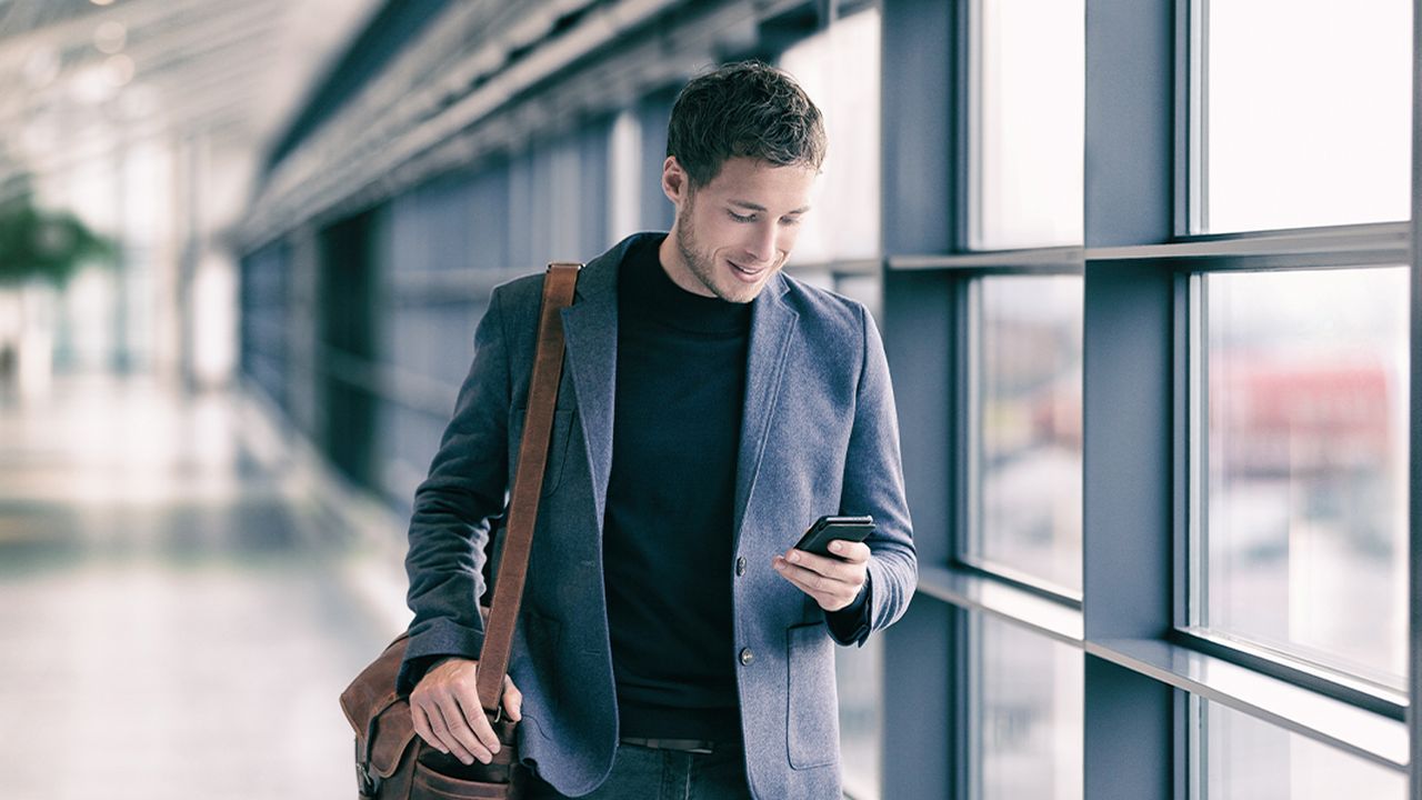 Employee walking through an office looking at their work phone