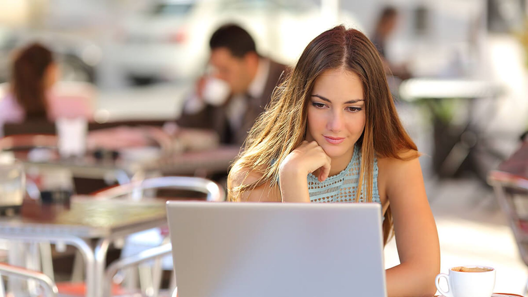 Stock photo of a feminine person using a laptop at a cafe