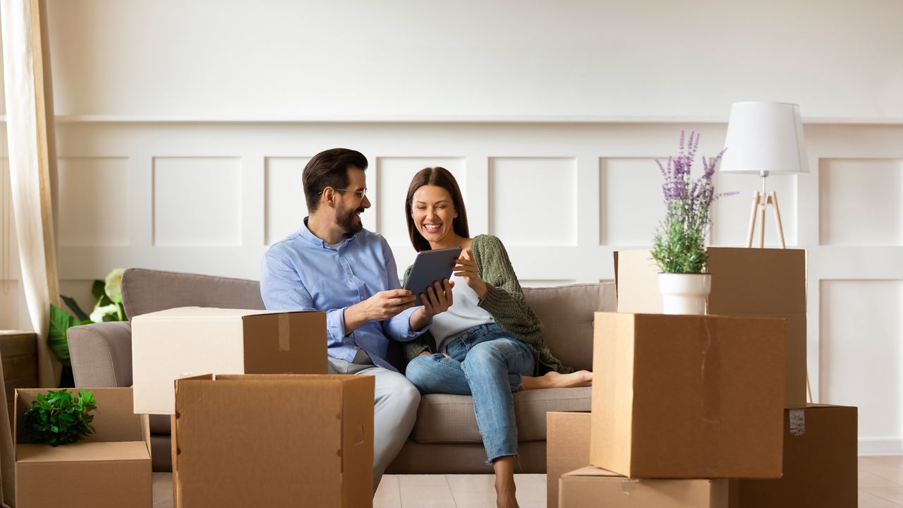 A couple moving house and sharing memories while they unpack photo frames