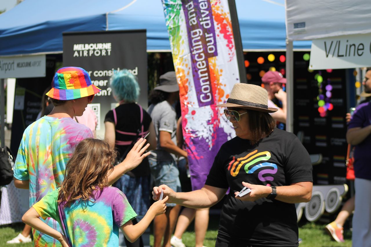 Aussie wearing pride shirt employees engages with attendees of the Midsumma Festival