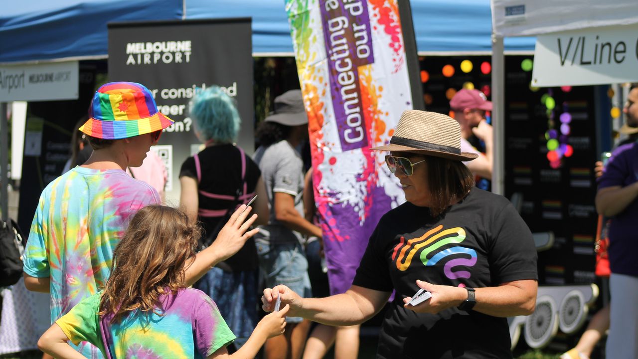 Aussie wearing pride shirt employees engages with attendees of the Midsumma Festival
