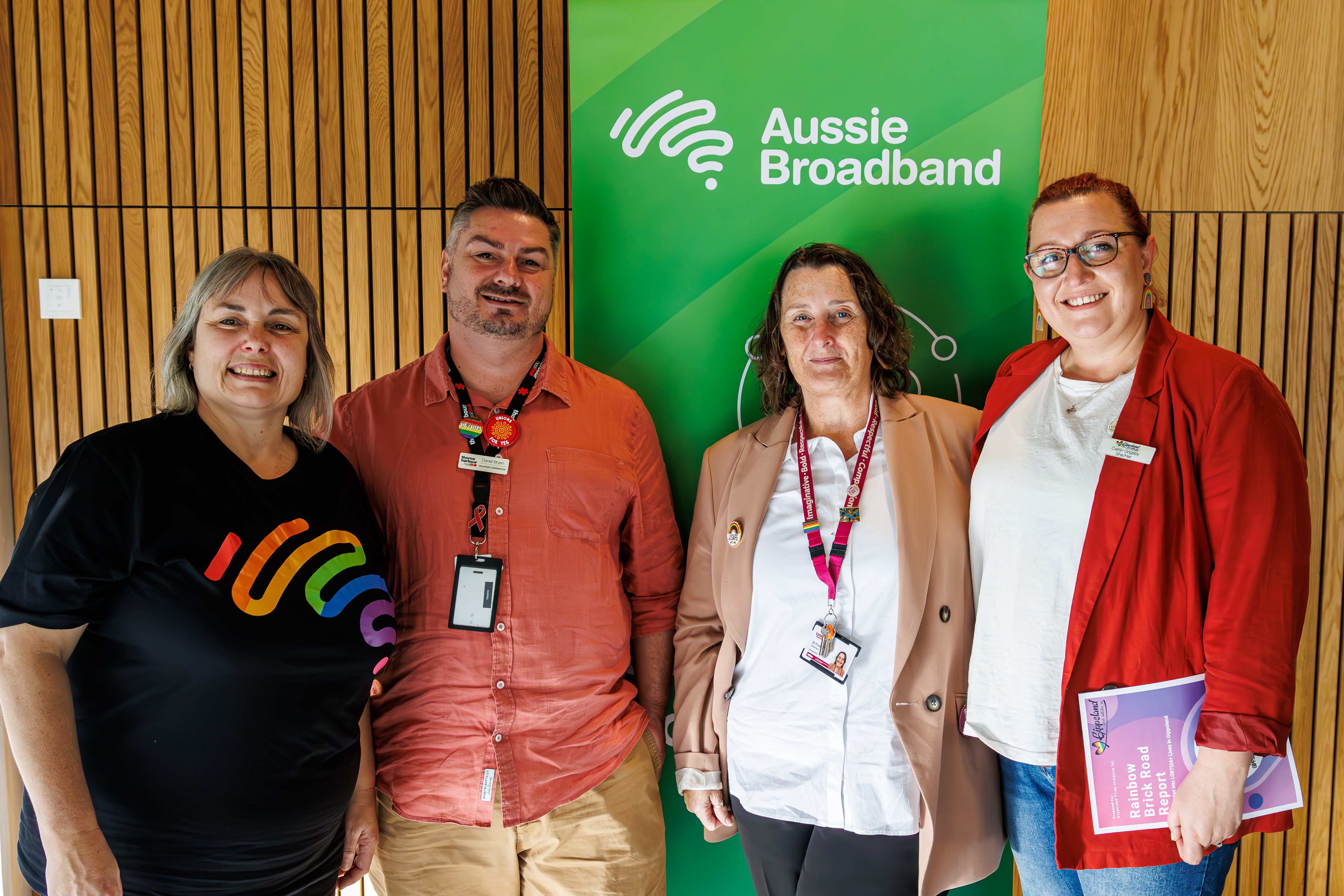 Representatives from Aussie Broadband and the Gippsland Pride Initiative pose in front of an Aussie Broadband Banner with the newly published Rainbow Road report