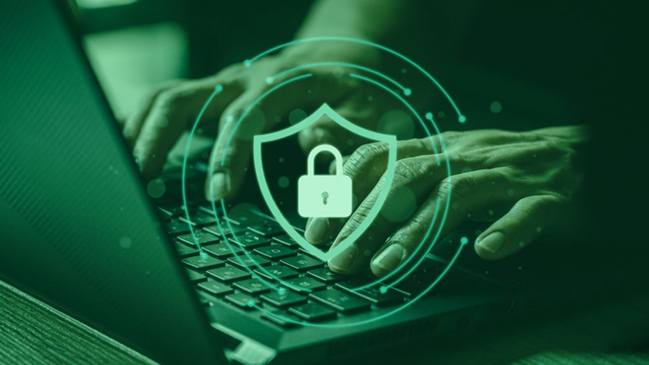 Hands typing on a laptop, which is placed on a desk. Superimposed onto the image is a slightly transparent green background, which gives the image a green tint. Superimposed at the front of the image is a locked padlock icon inside a shield. surrounding the shield are several circular lines with dots on each end.