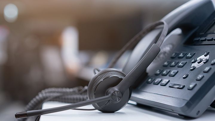A phone headset on a desk placed in front of a phone handset.