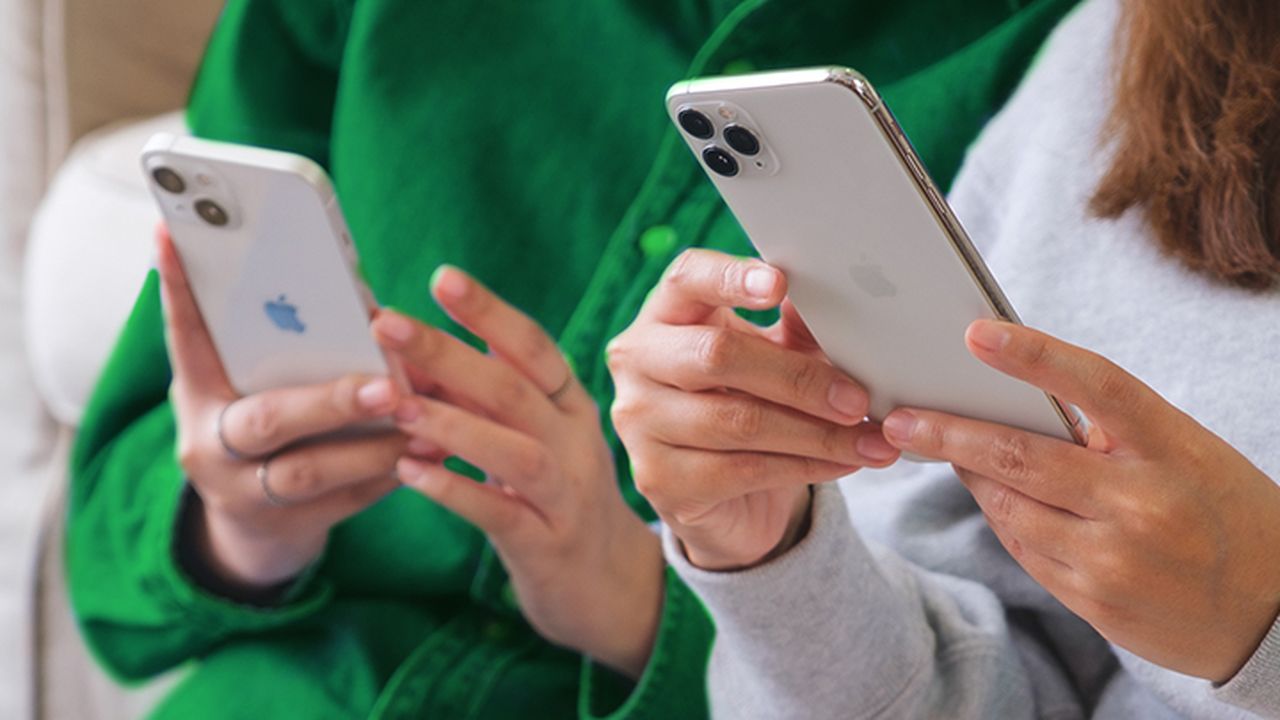 two people with their faces out of frame each holding a mobile phone with both hands.