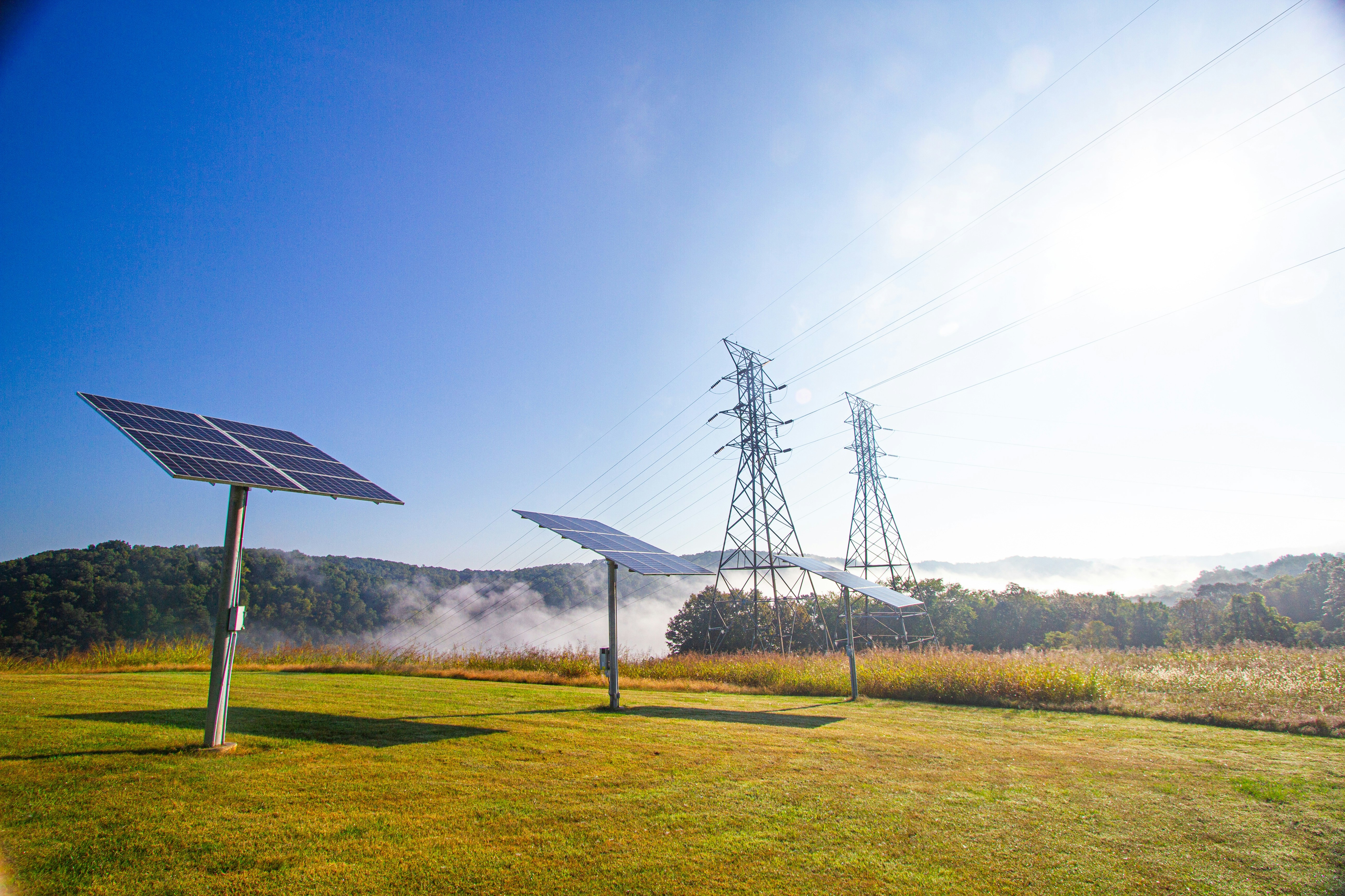 Ground-mount solar panels with electrical towers in the background