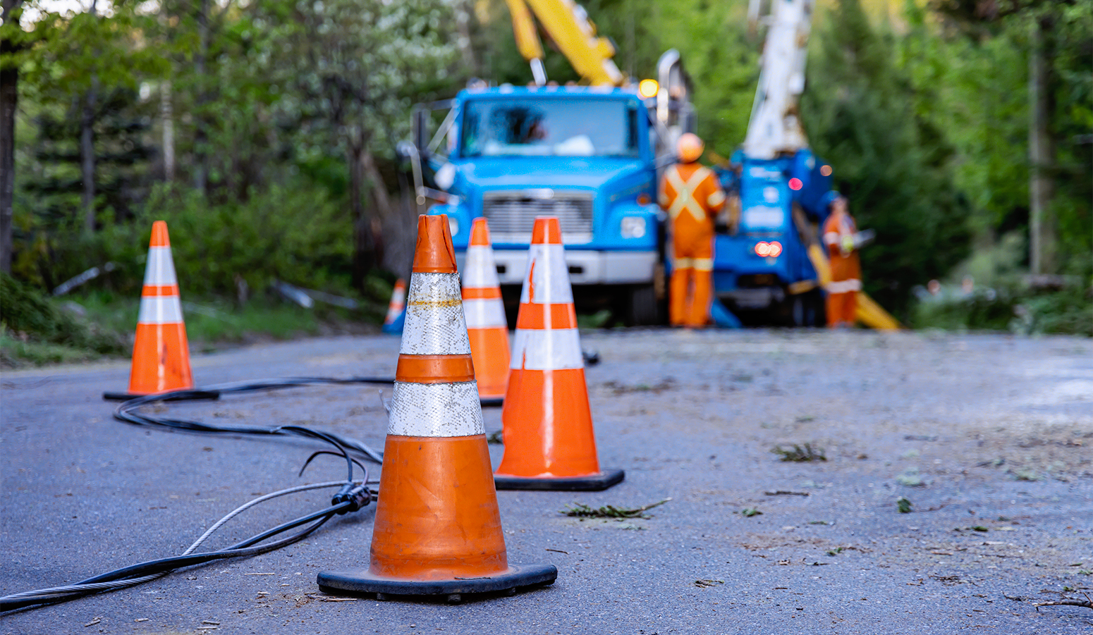 Orange cones on the street blocking off workers fixing a power line.