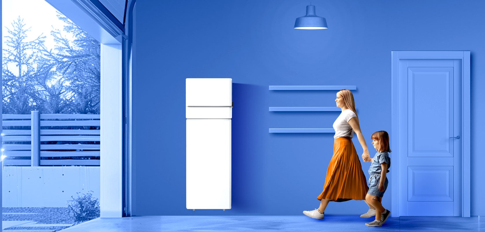 Women holding the hand of a child as they walk past a wall-mounted battery