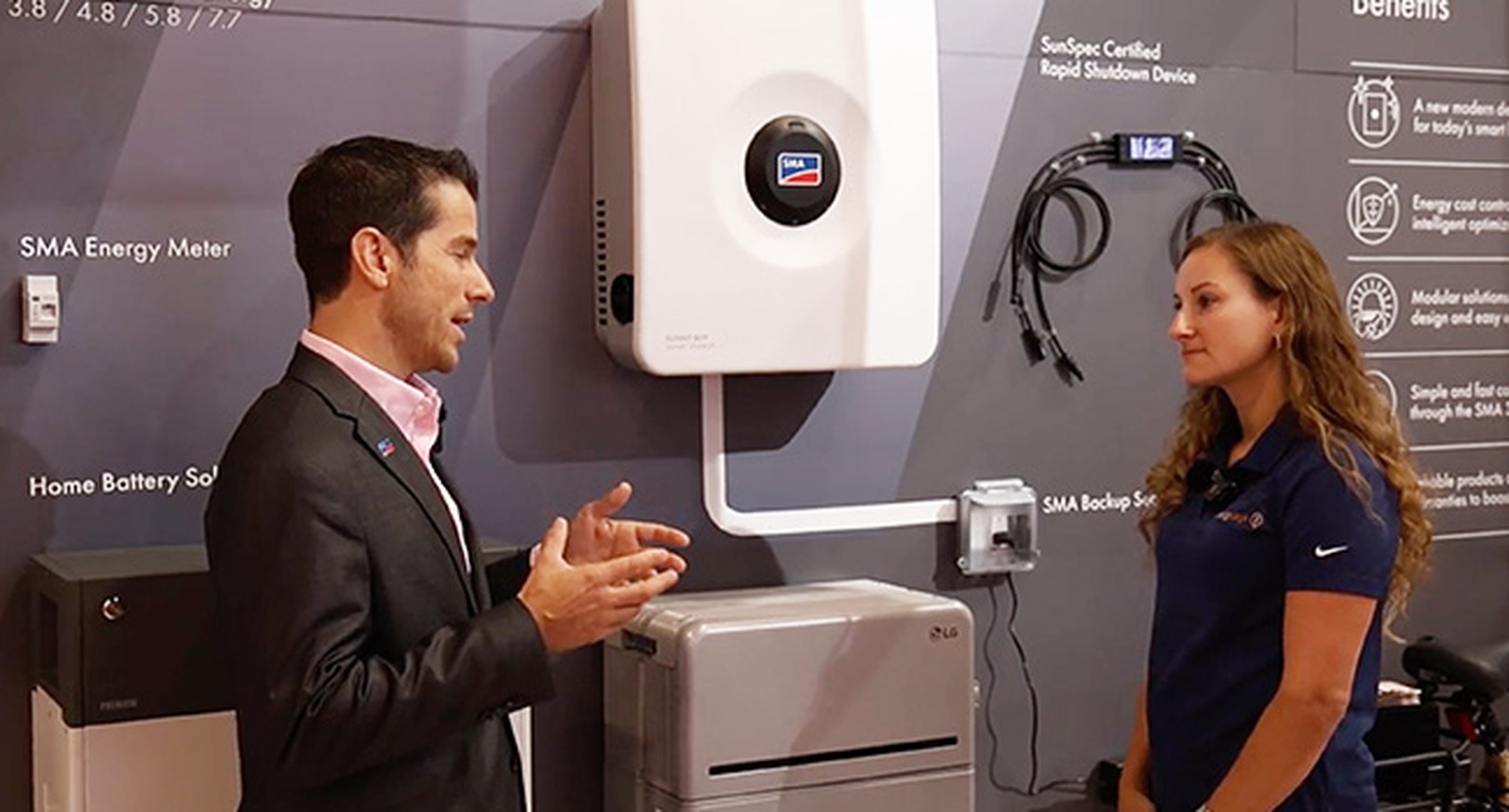 Two people talking in front of SMA home energy system