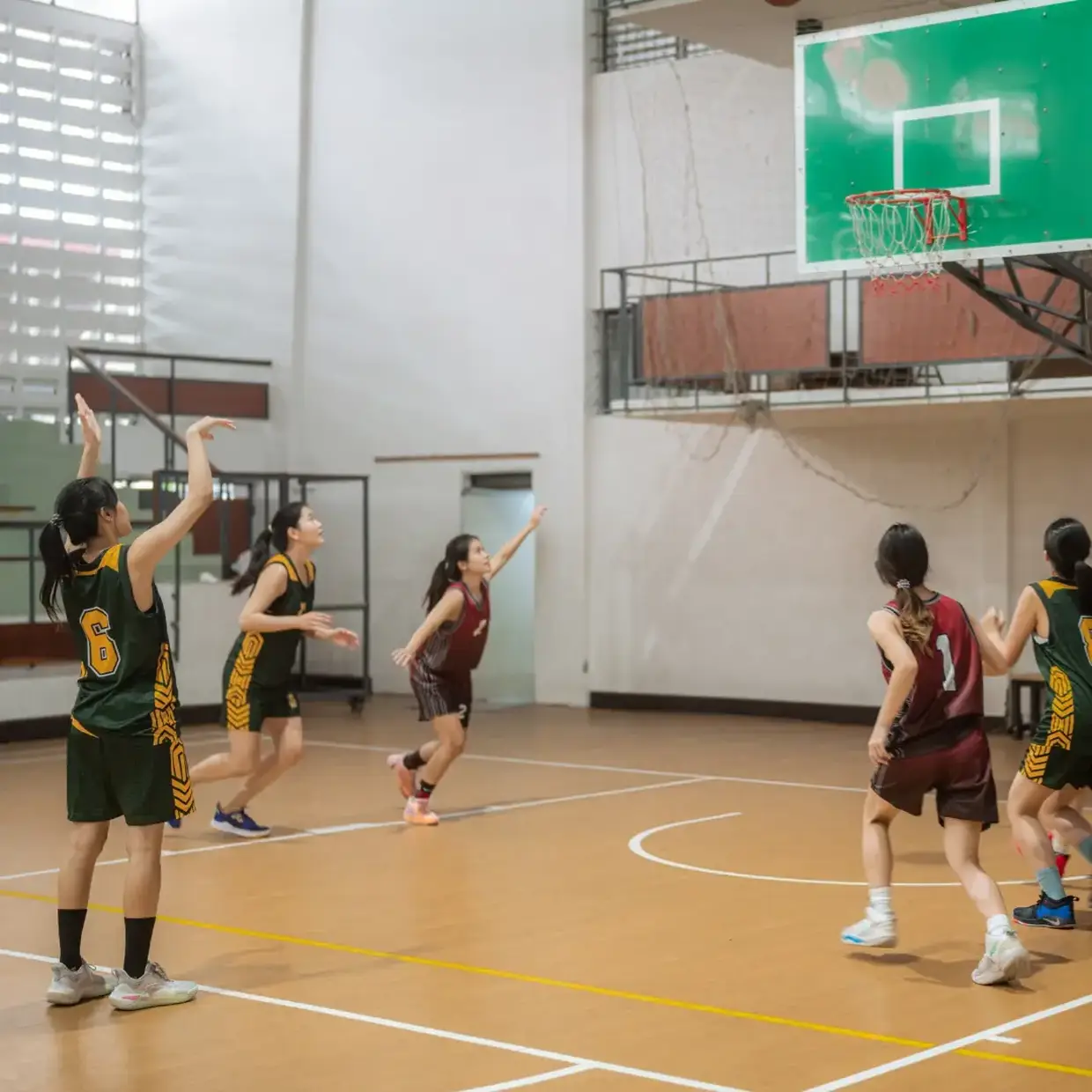 Girl basketball player shooting free throw and players getting ready for the rebound.