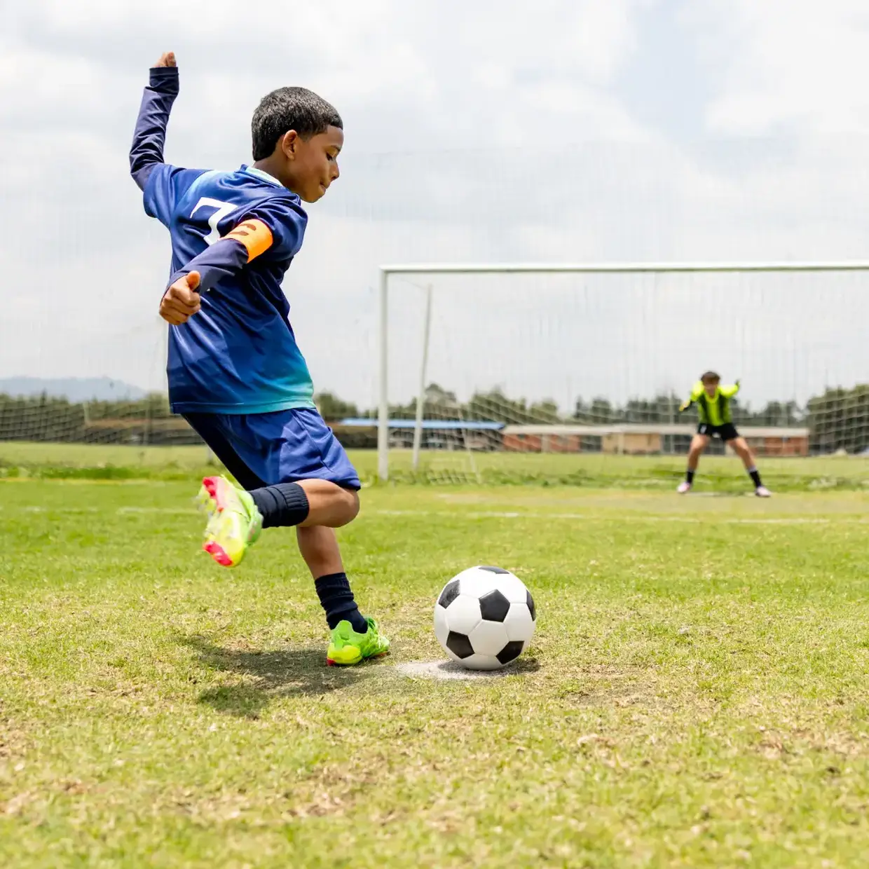 Young player in a blue uniform kicks toward goal, featured on a soccer fundraiser page.