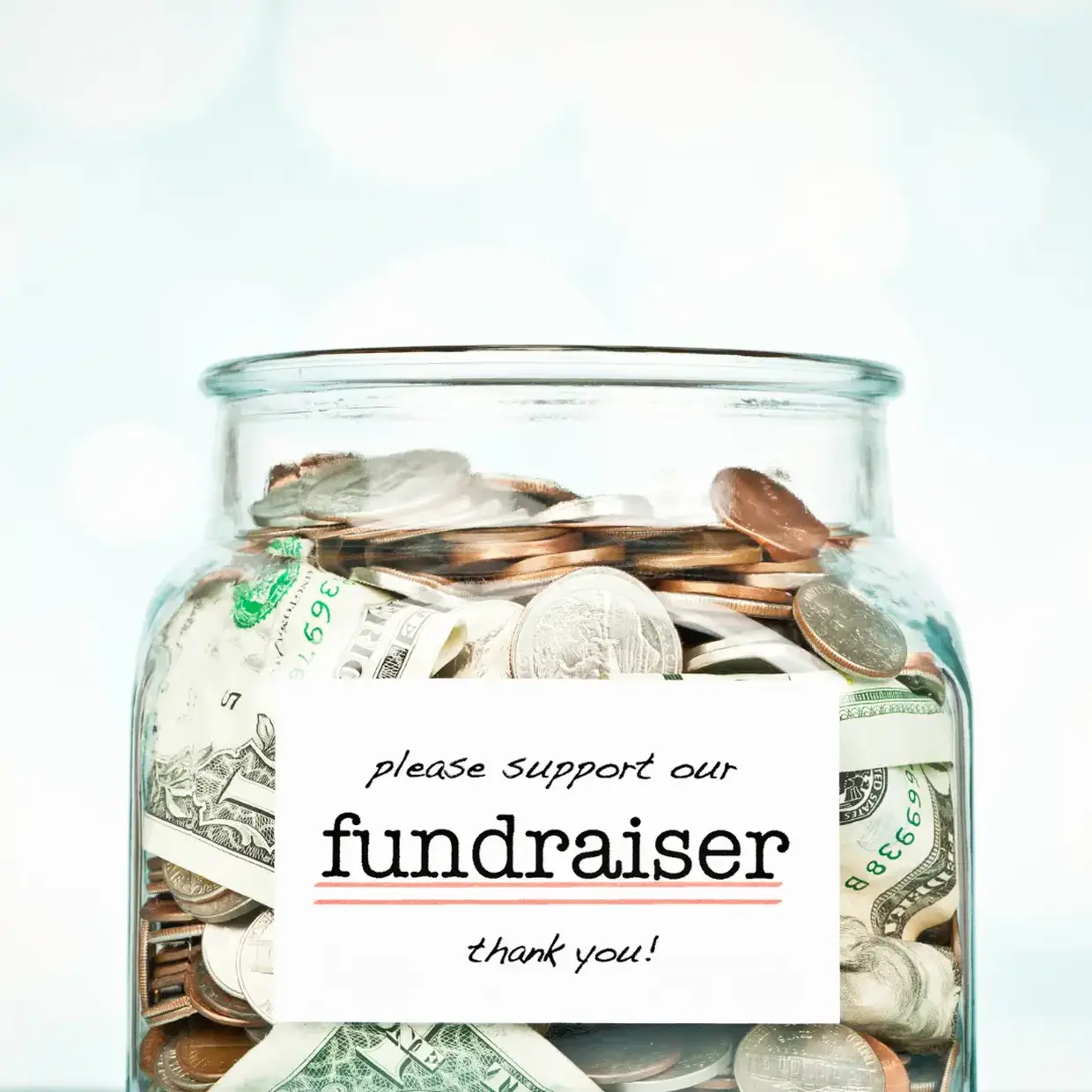Donation jar filled with cash and coins with a “please support our fundraiser” sign, representing the Best Fundraiser for groups and community fundraising.