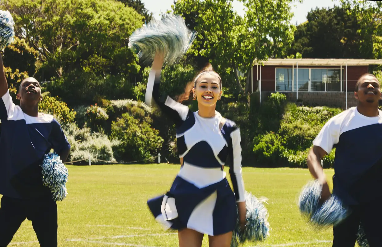 Cheerleaders practicing with pom poms on the sports field