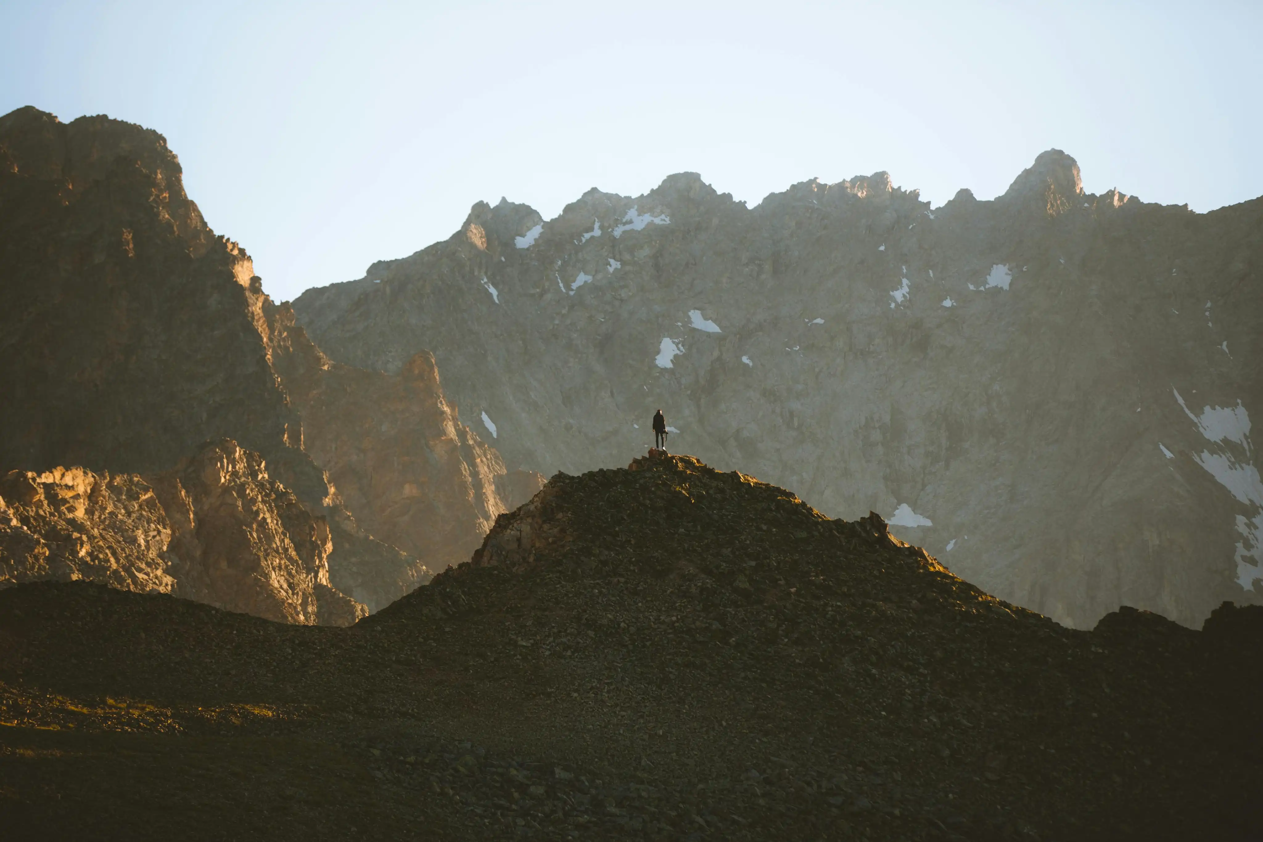 A person standing on a mountain ridge at sunrise
