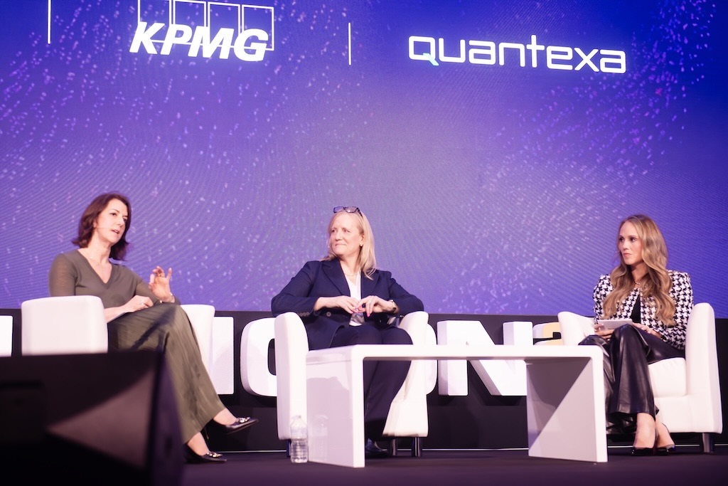 Three women engaged in a panel discussion on stage, with KPMG and Quantexa logos displayed above them.