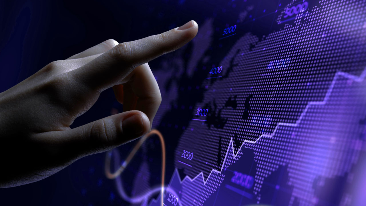 Hand pointing at a digital world map with upward-trending graphs and numbers, symbolizing global financial growth and data analysis.
