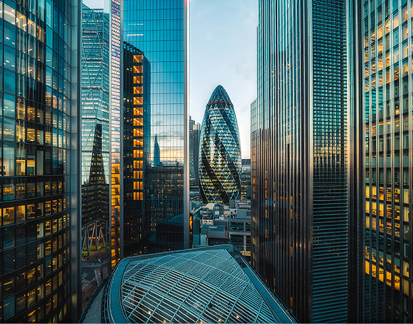 Cityscape view of modern skyscrapers with reflective glass facades, including a distinctive bullet-shaped building, at sunset.