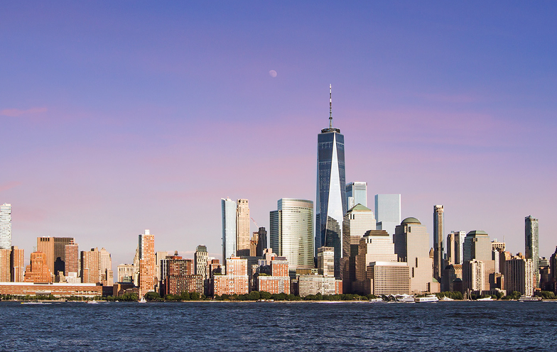 Skyline of a city with modern skyscrapers, including a tall building with a spire, under a clear sky with a visible moon above a river.