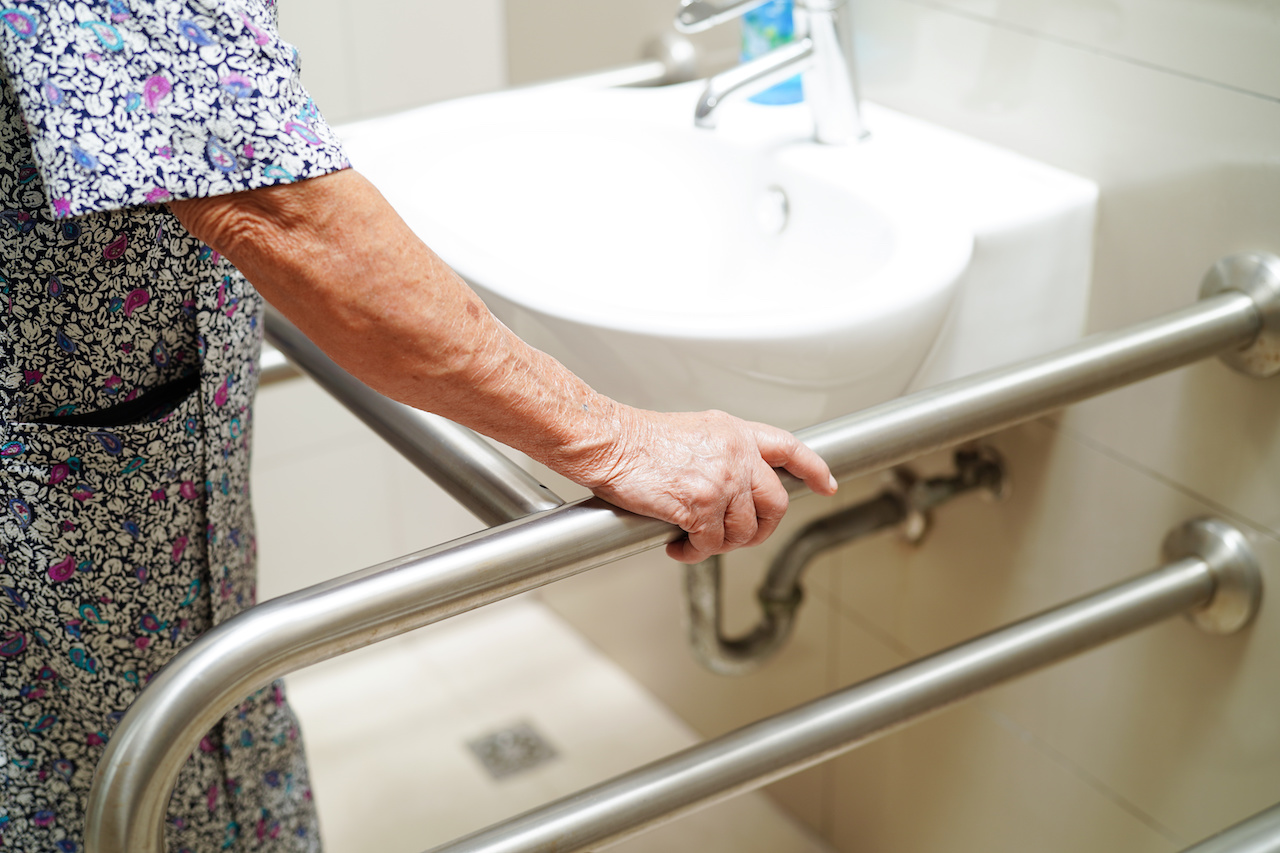 Older-adult-holding-grab-bar-near-bathroom-sink