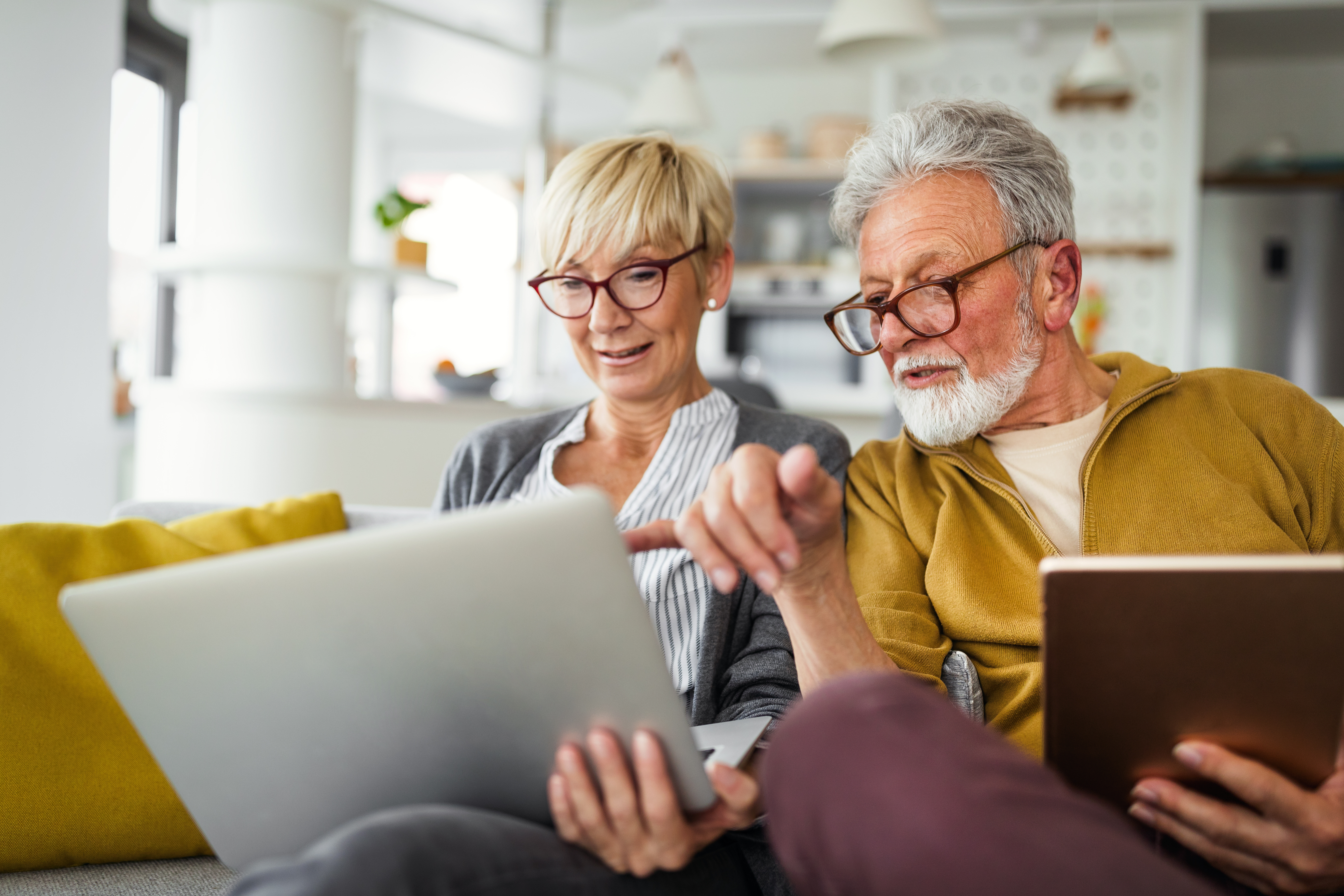 two-older-adults-using-laptop-and-tablet