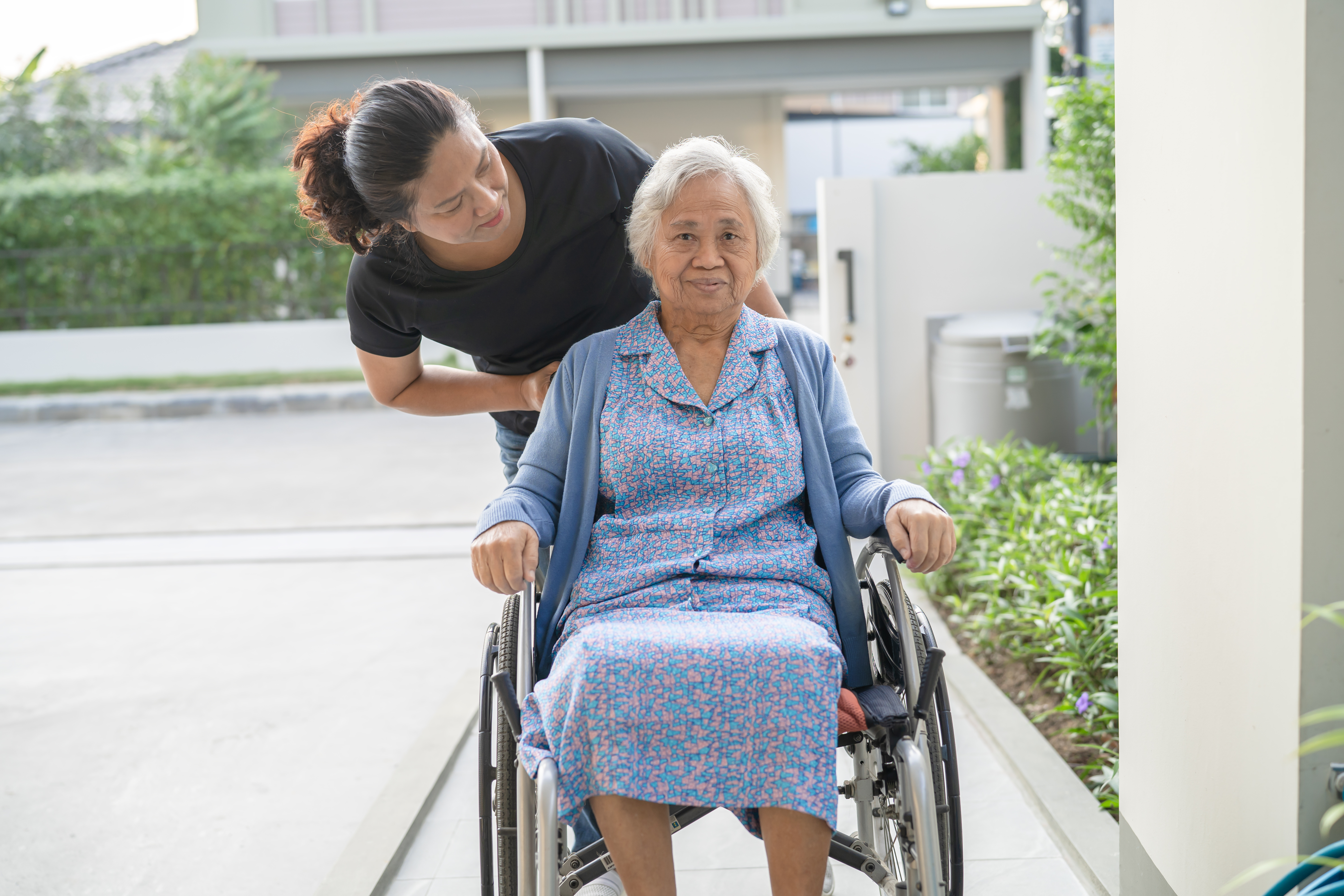 women-in-wheelchair-being-pushed-up-home-ramp-by-caregiver