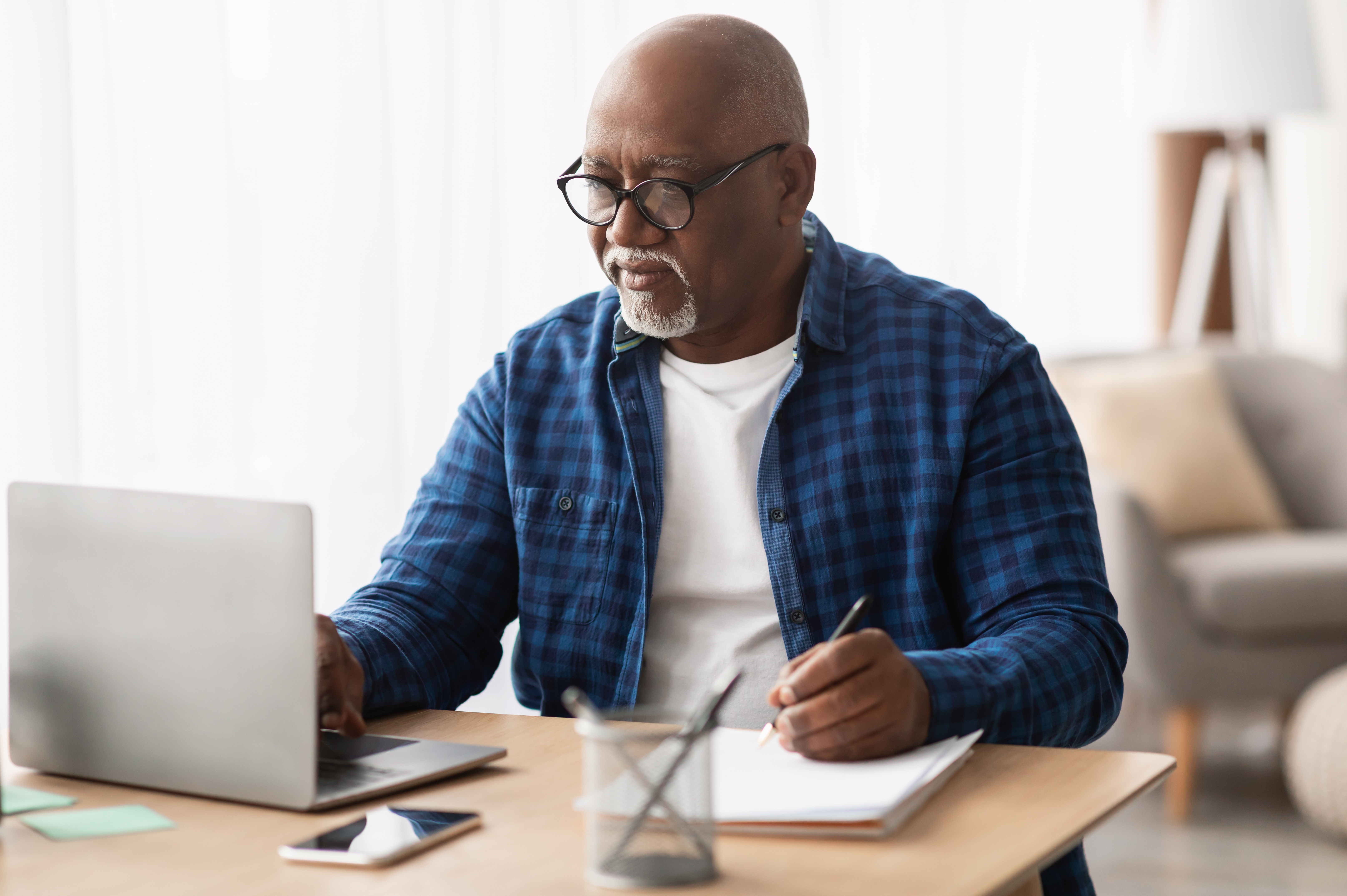 older-adult-looking-at-computer-and-writing