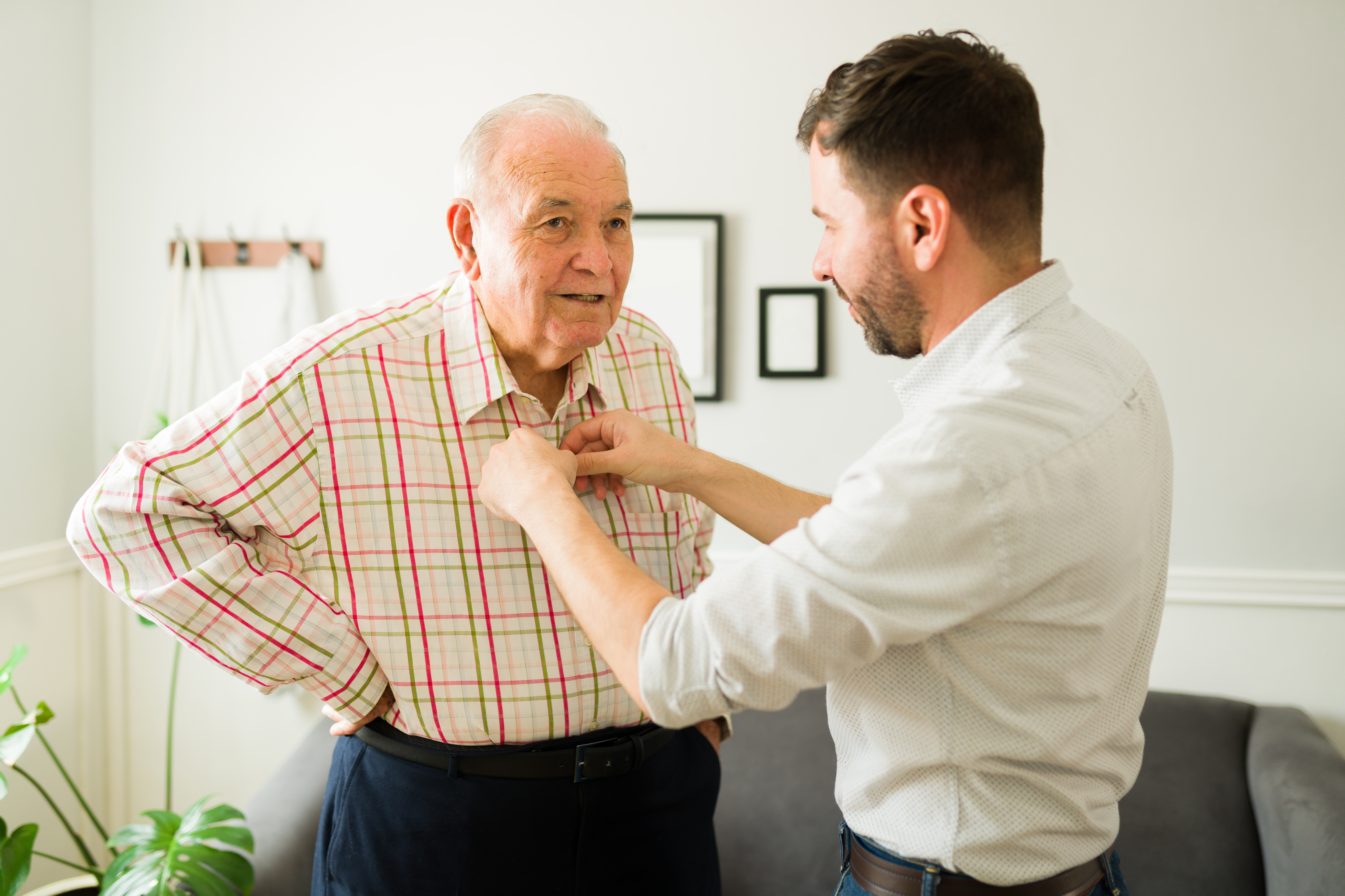adult-child-helping-older-adult-button-their-shirt