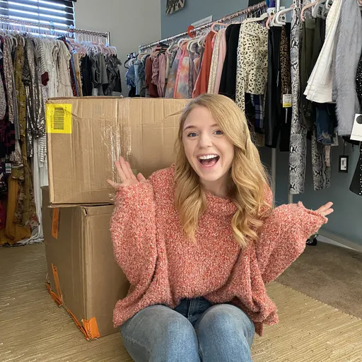 Lindsay sitting in front of racks and boxes full of clothes