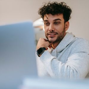 Man looking at a laptop screen from a low perspective behind the device