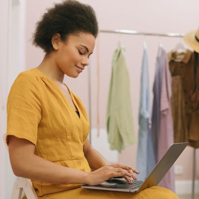 Female business owner sitting in a retail store working on a laptop