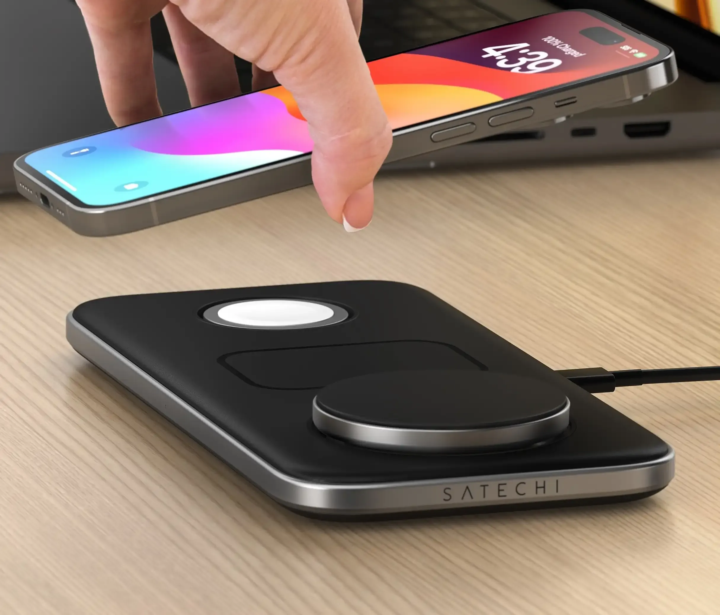 A hand placing an iPhone onto a Qi2 Trio Wireless Charging Pad.