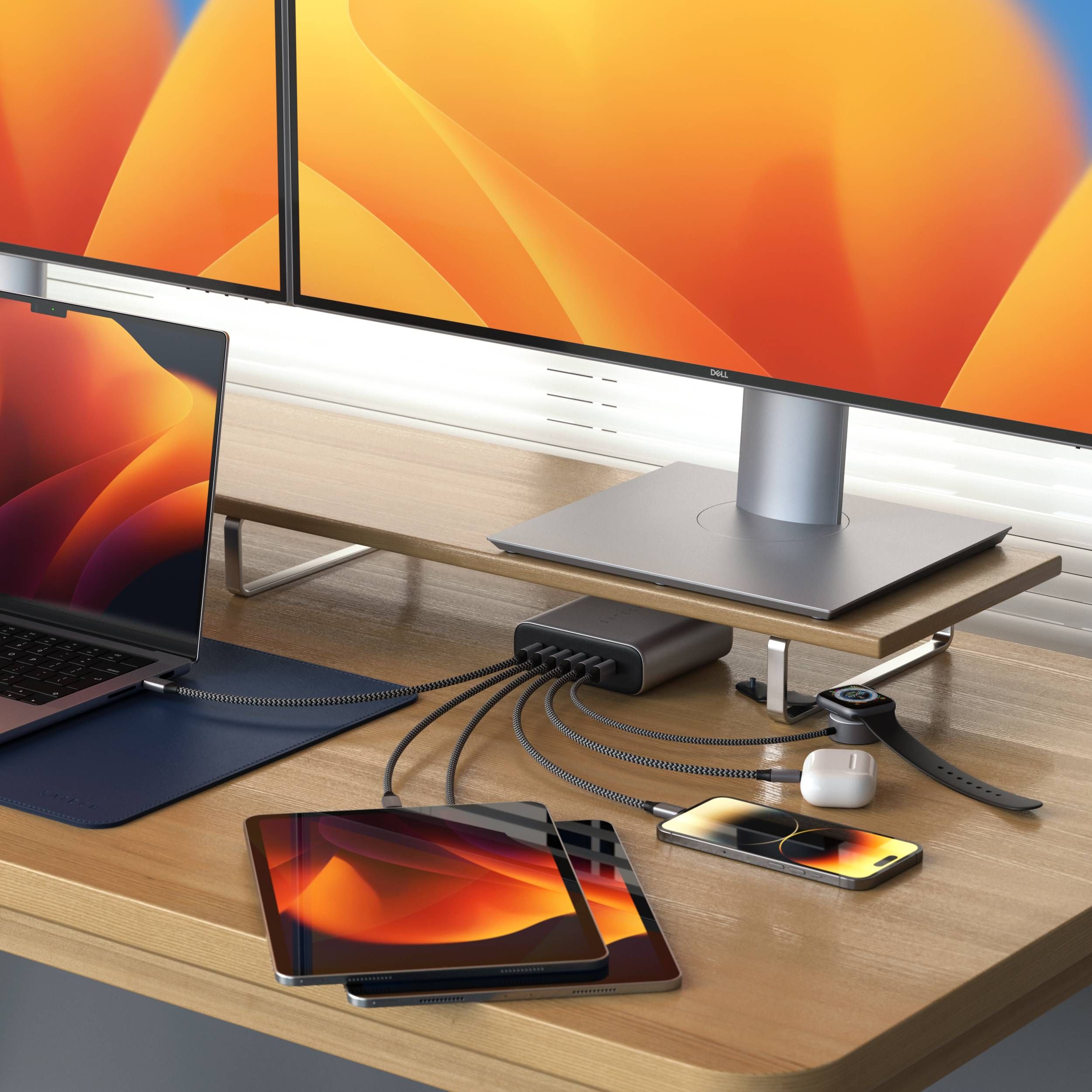 A 200W USB-C 6-Port GaN Charger charging a Macbook, two iPads, iPhone, AirPods, and Apple Watch on a modern desk with two external monitors.