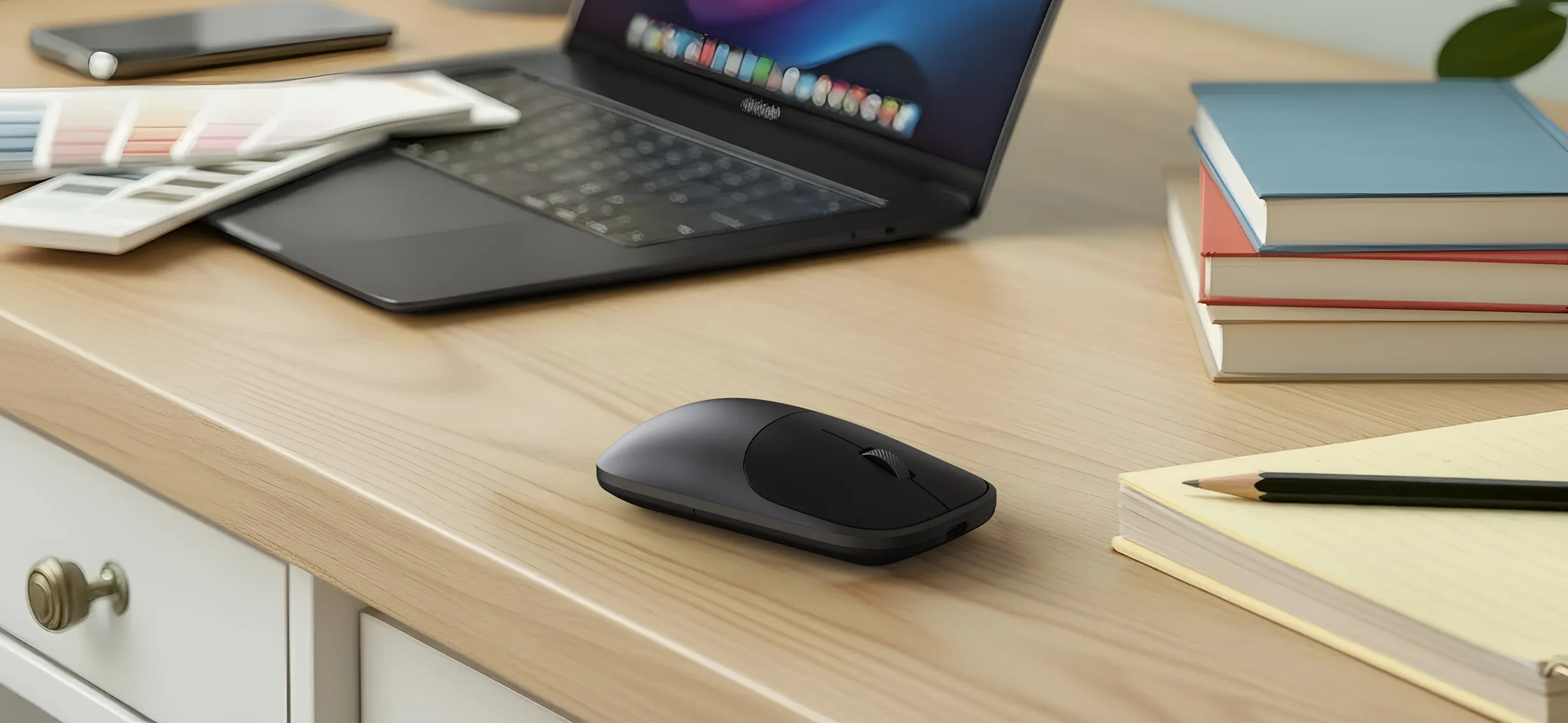 A closeup of a Slim EX Wireless Mouse on a desk alongside a Macbook.