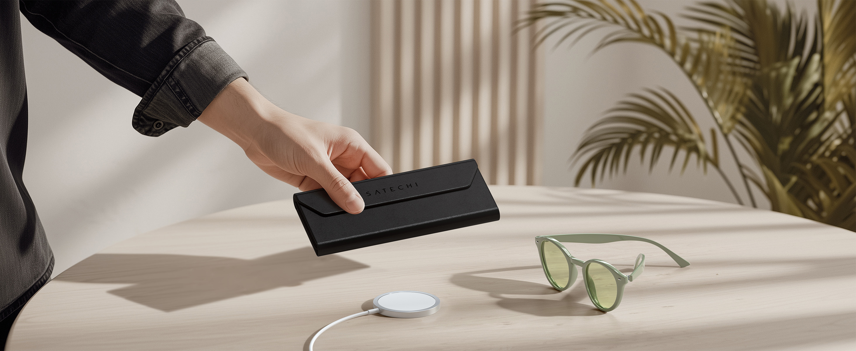 A person placing a Vegan-Leather FindAll™ Glasses Case on Satechi USB-C Magnetic Wireless Charging Cable.