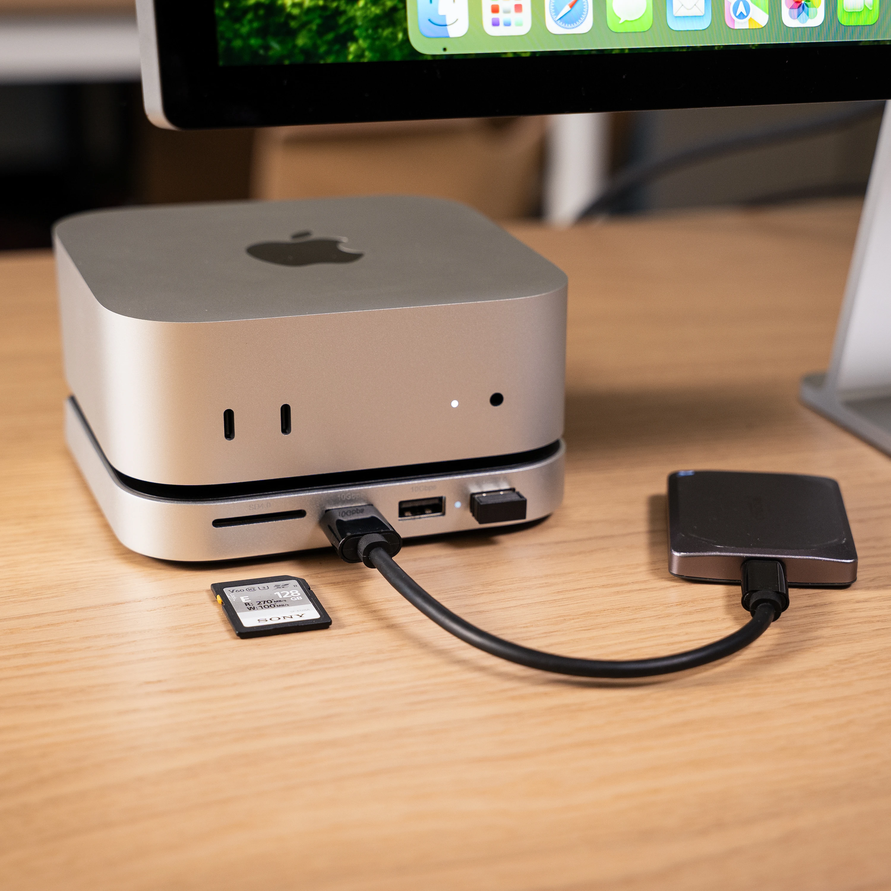 Satechi Mac Mini M4 Stand & Hub with SSD Enclosure, shown connected to an SD card, external hard drive, and USB flash drive, demonstrating its compatibility with multiple storage devices.