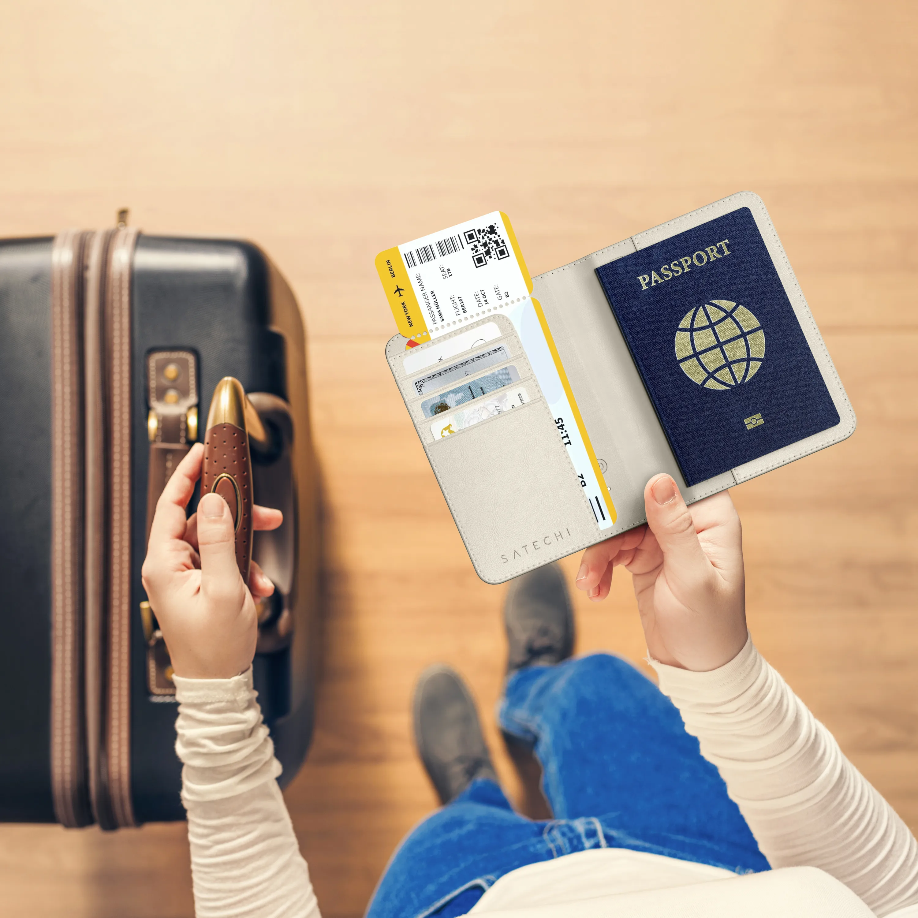Person holding a Satechi FindAll™ Passport Cover and suitcase.