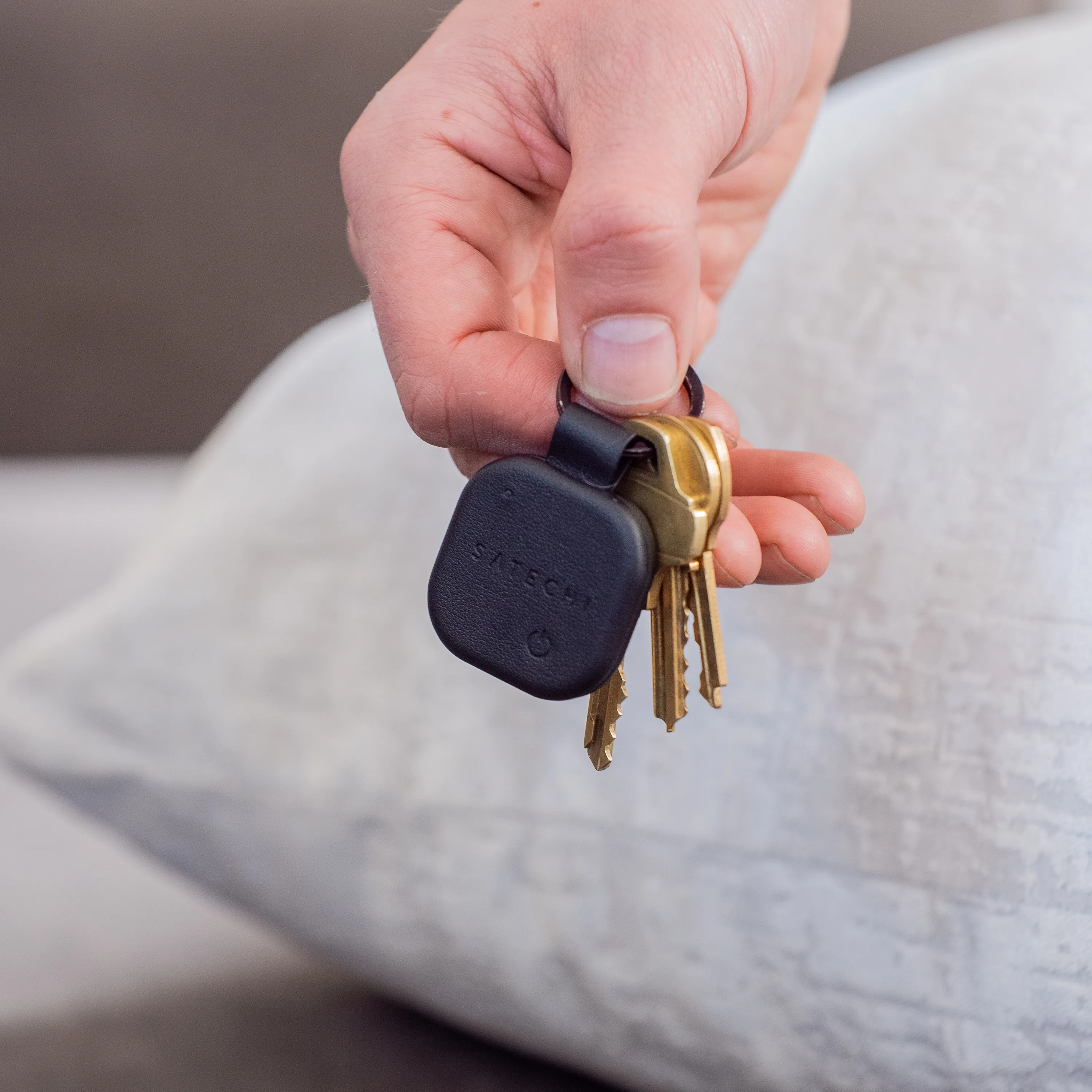 A hand holding a Satechi Vegan-Leather FindAll™ Keychain with keys attached.