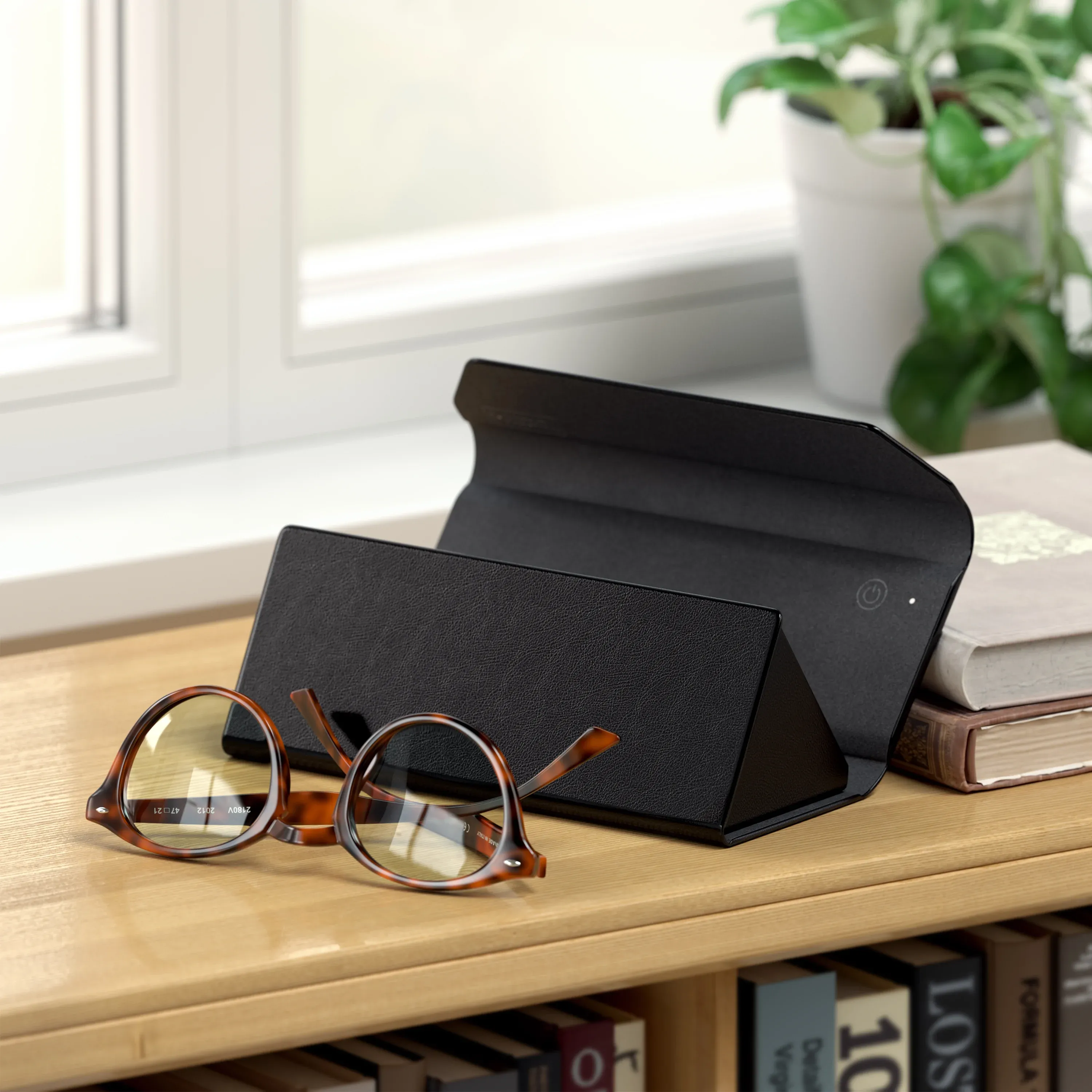 An open Vegan-Leather FindAll™ Glasses Case with reading glasses next to it, on a bookcase.